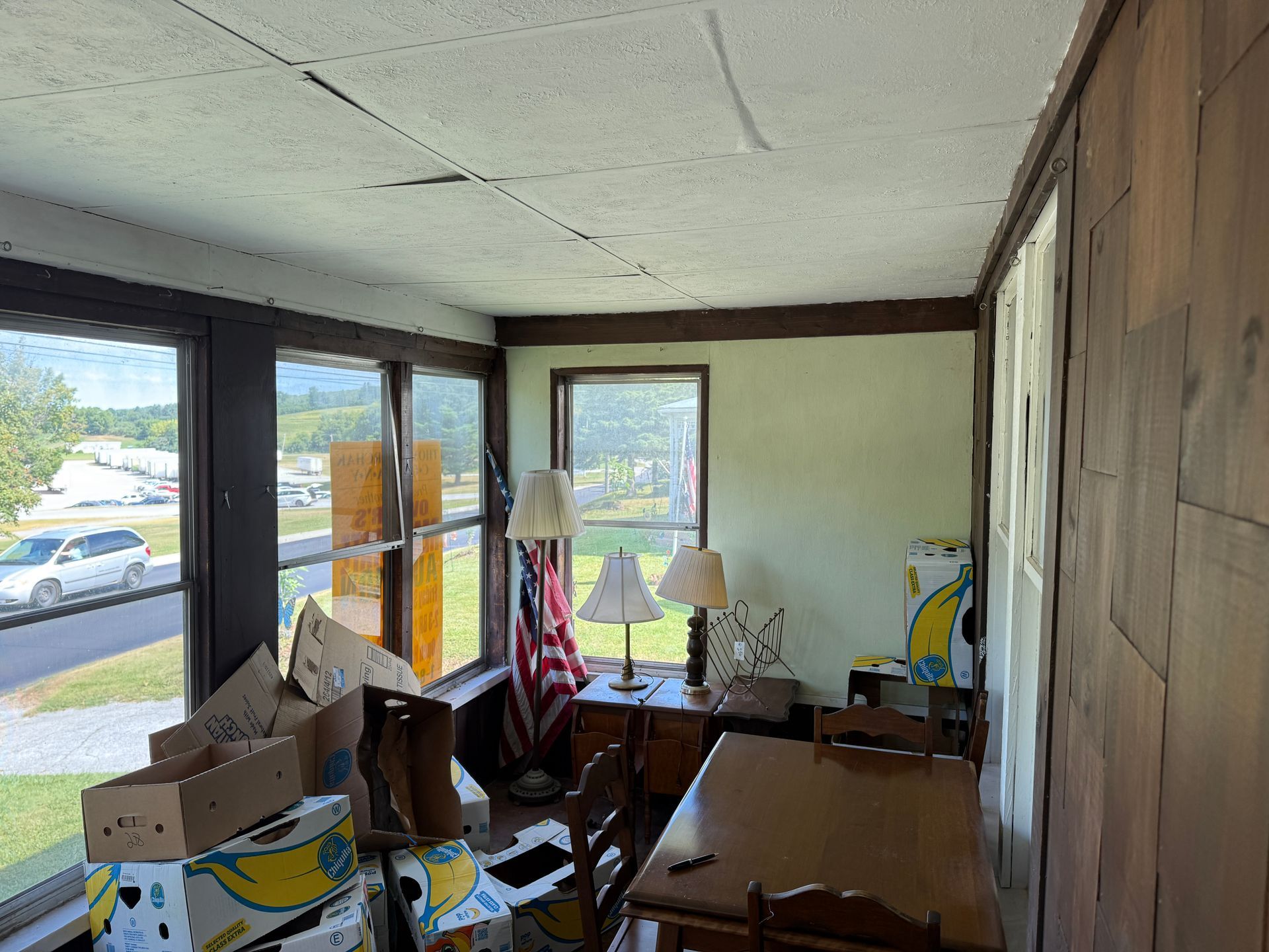 Interior room with wood paneling, windows, furniture, and boxes.