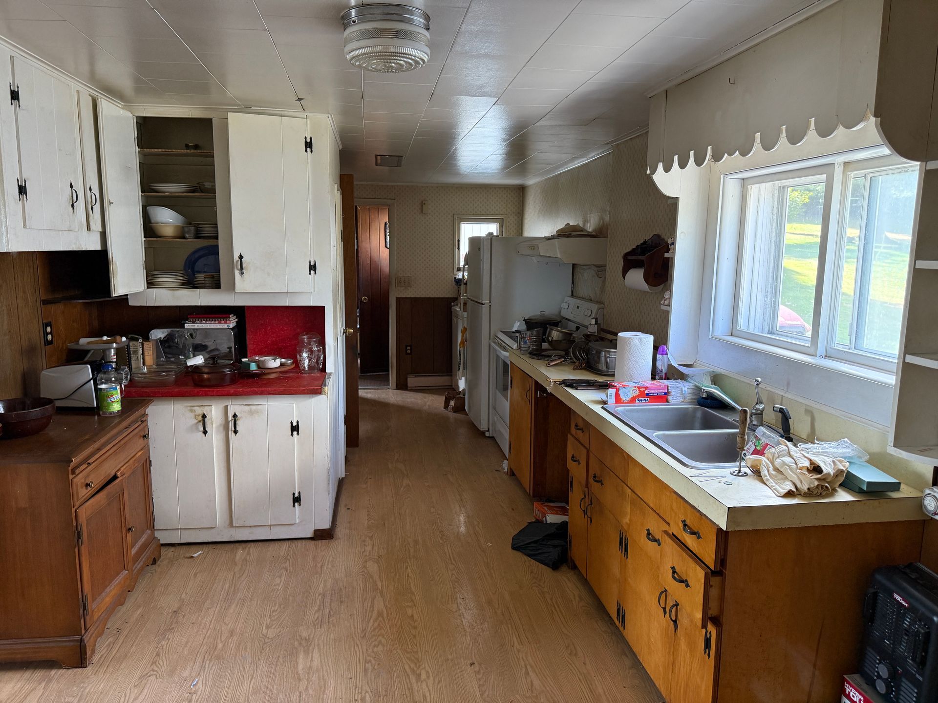 A kitchen with white and wood cabinets, a window, and appliances.