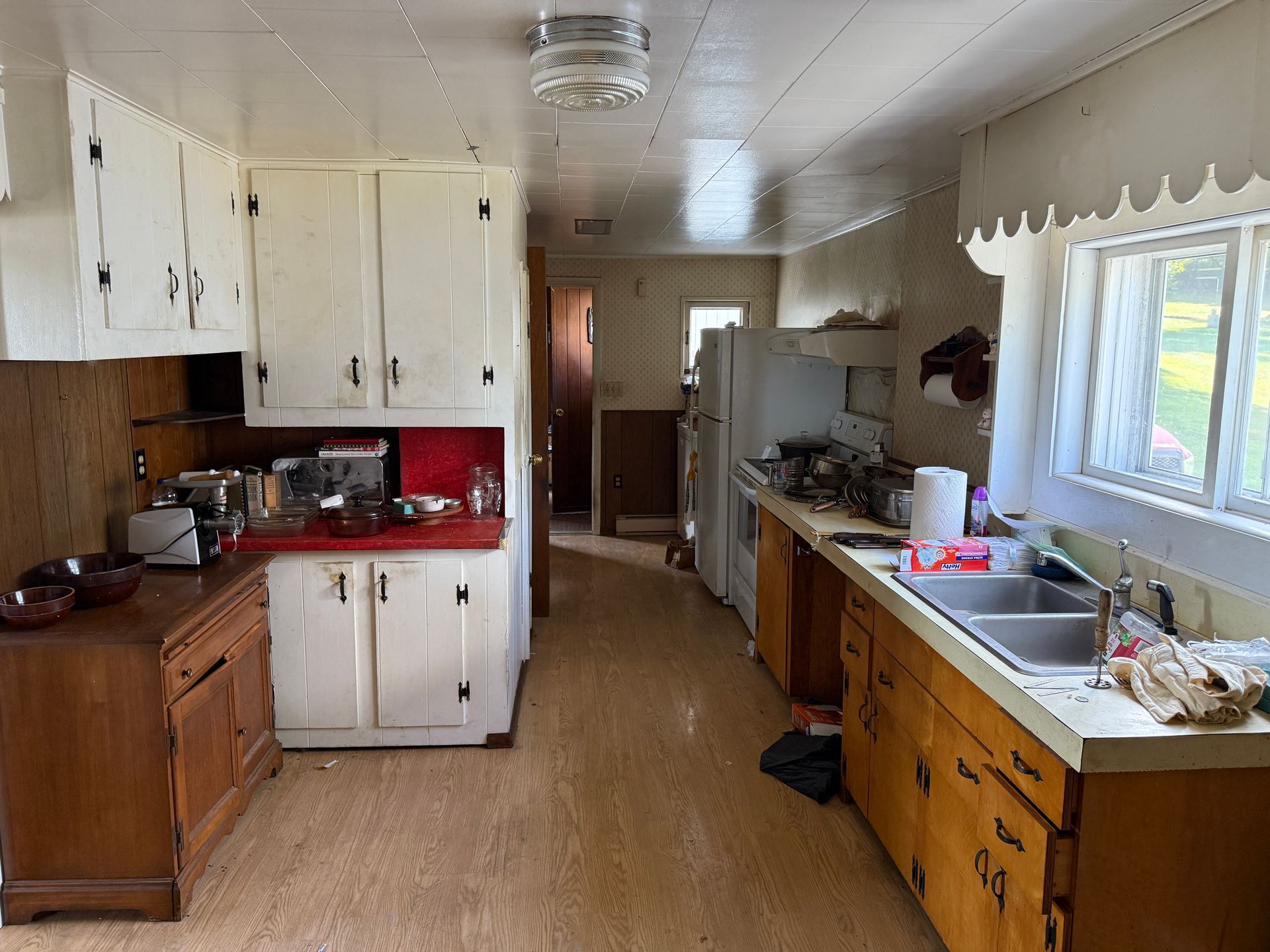 Kitchen with white and wood cabinets, red countertop, and a window.