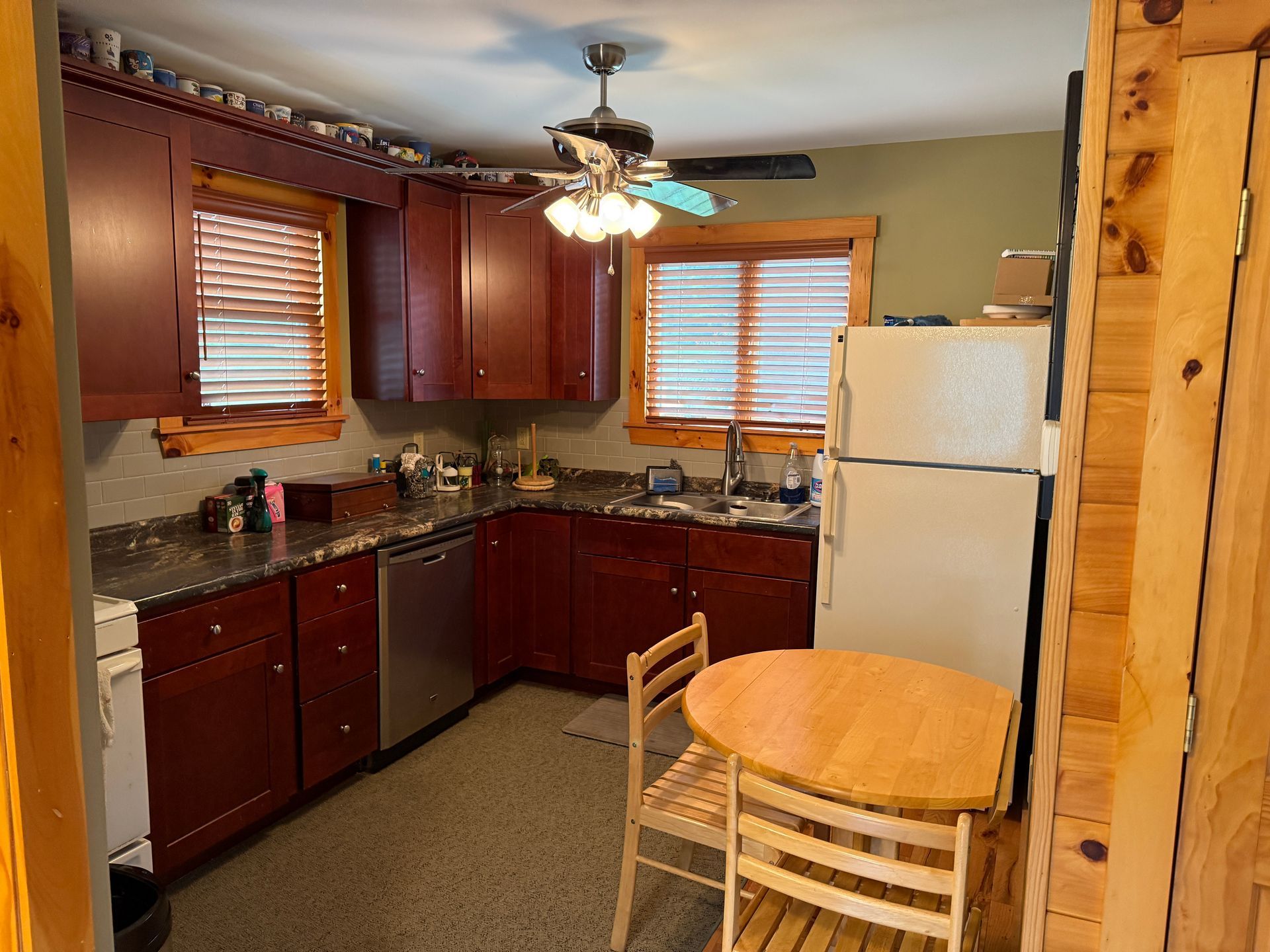 Kitchen with dark red cabinets, round table, and a refrigerator.