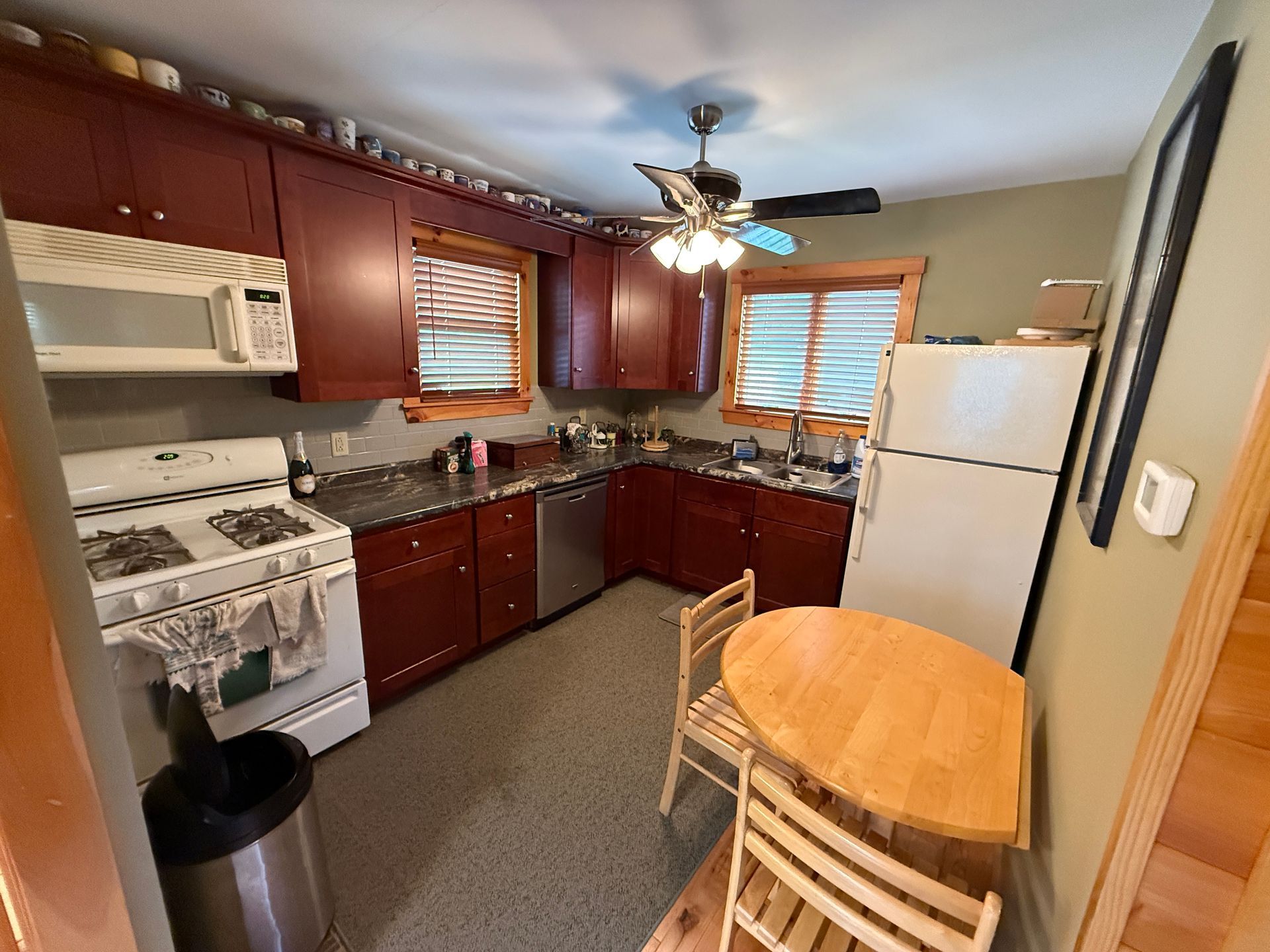 Small kitchen with red cabinets, stainless steel appliances, and a small wooden table.