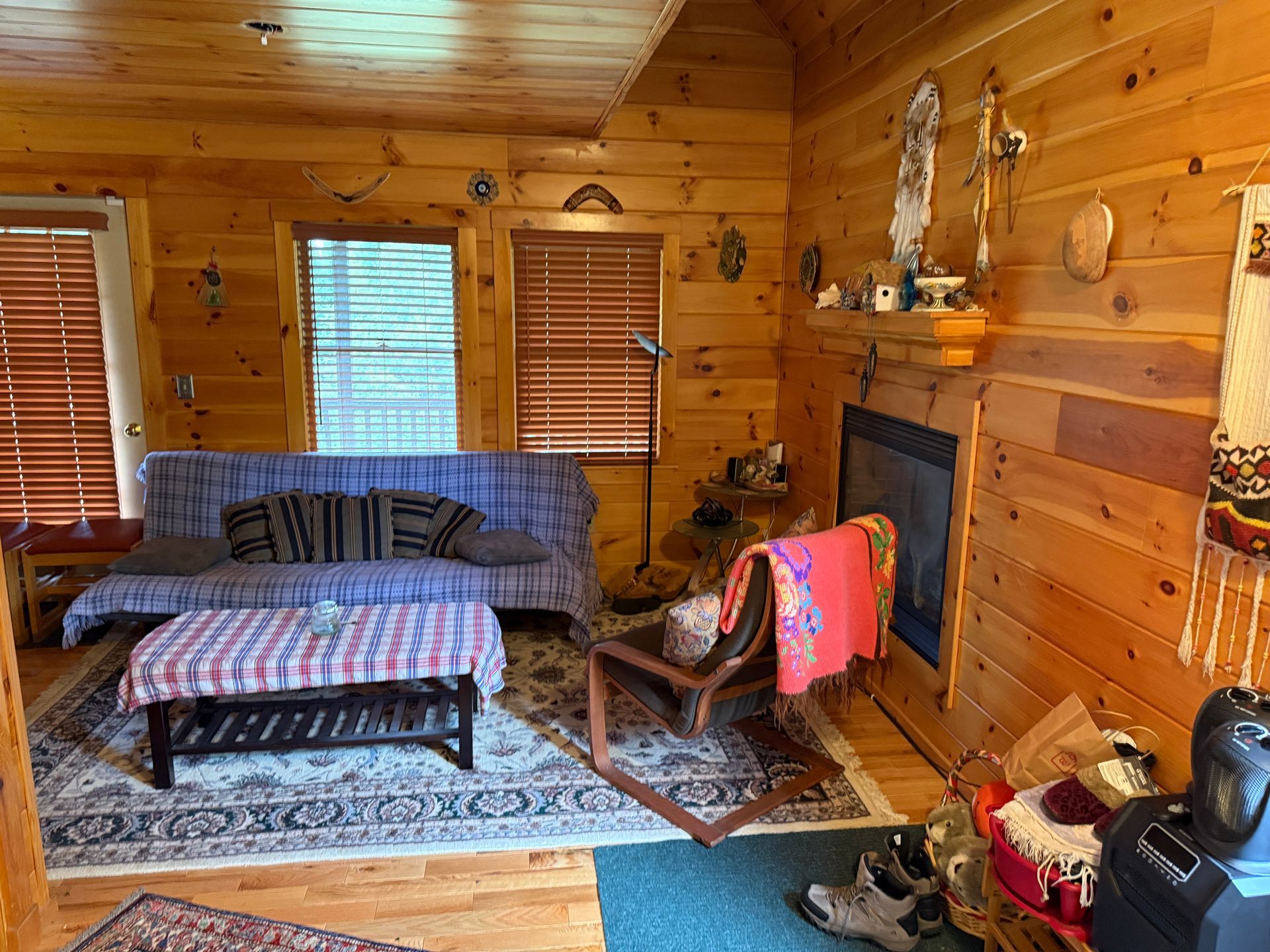 Wooden cabin interior with a sofa, fireplace, and rustic furnishings.