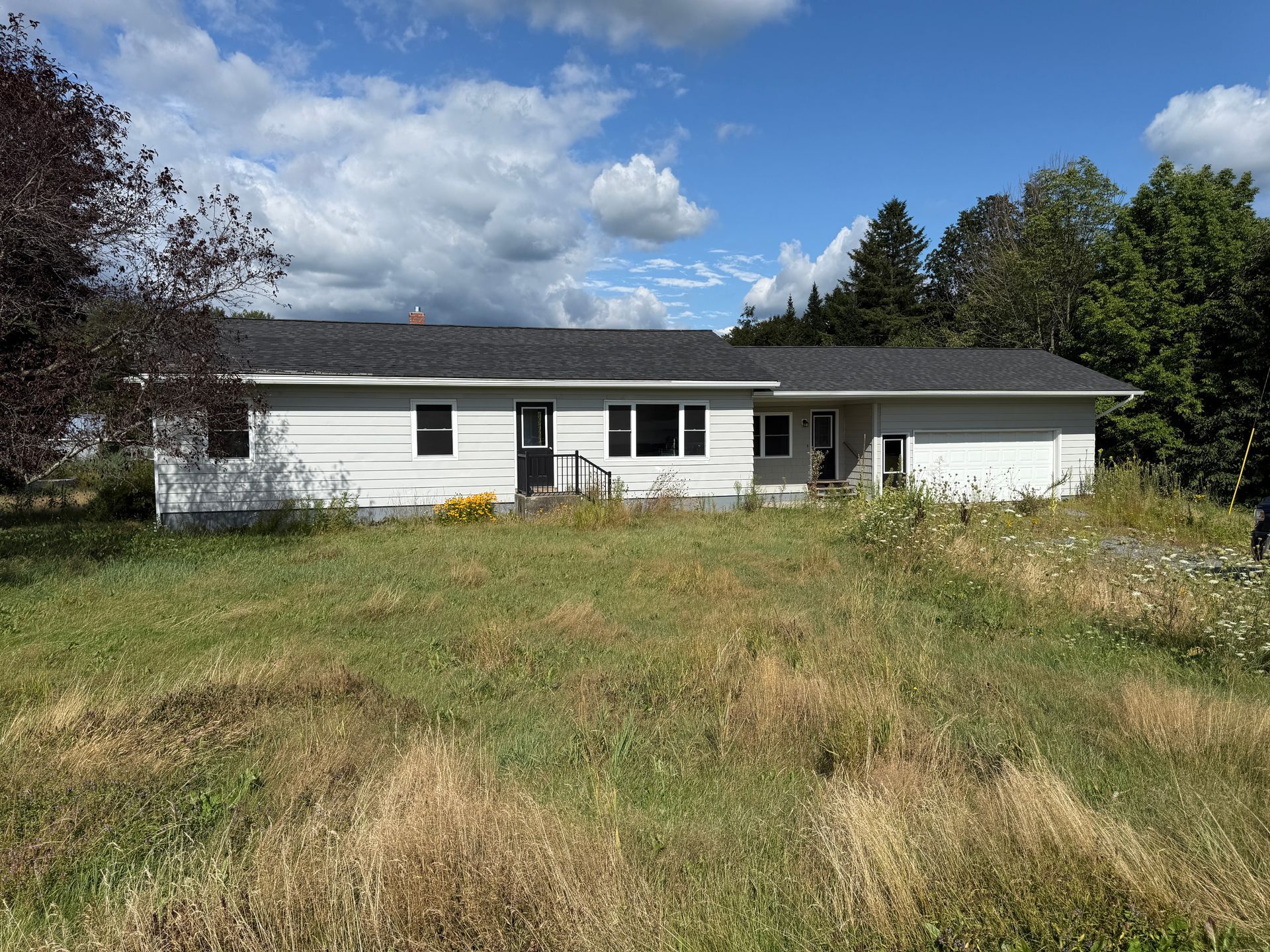 White ranch-style house on a grassy hill.