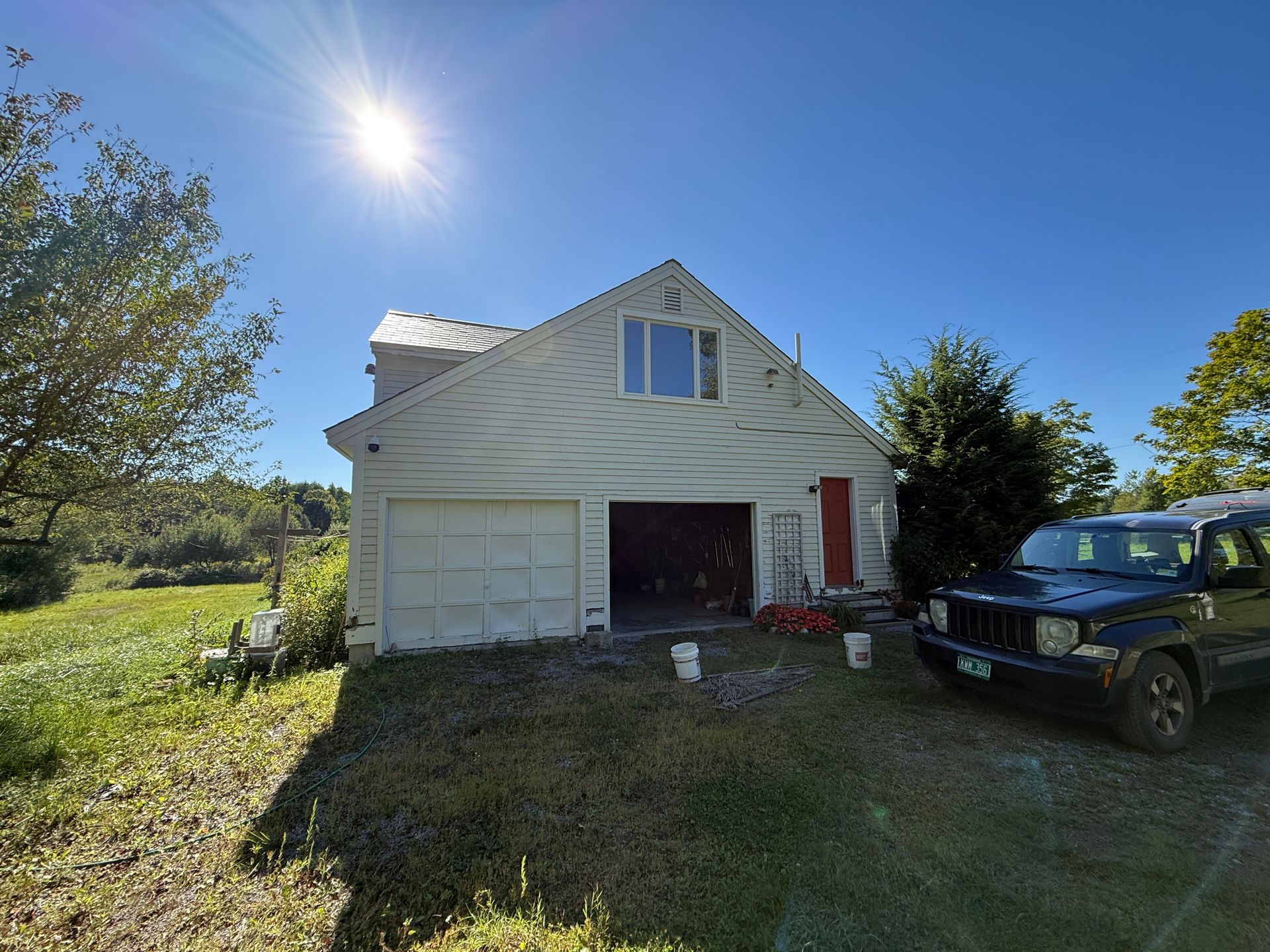 White garage with open door, Jeep parked, sunny day.