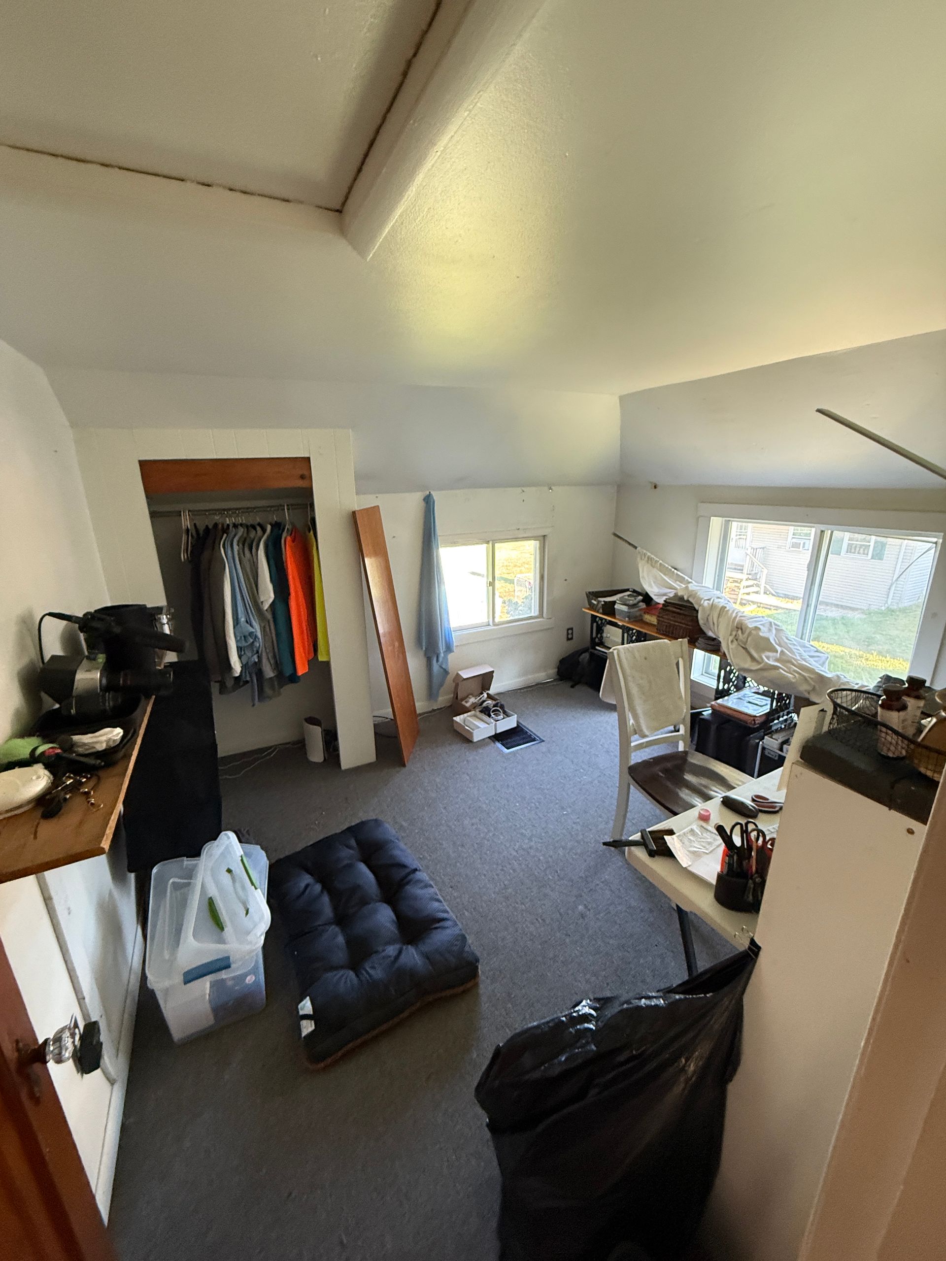 Room with closet, window, and various objects. Gray carpet, white walls.