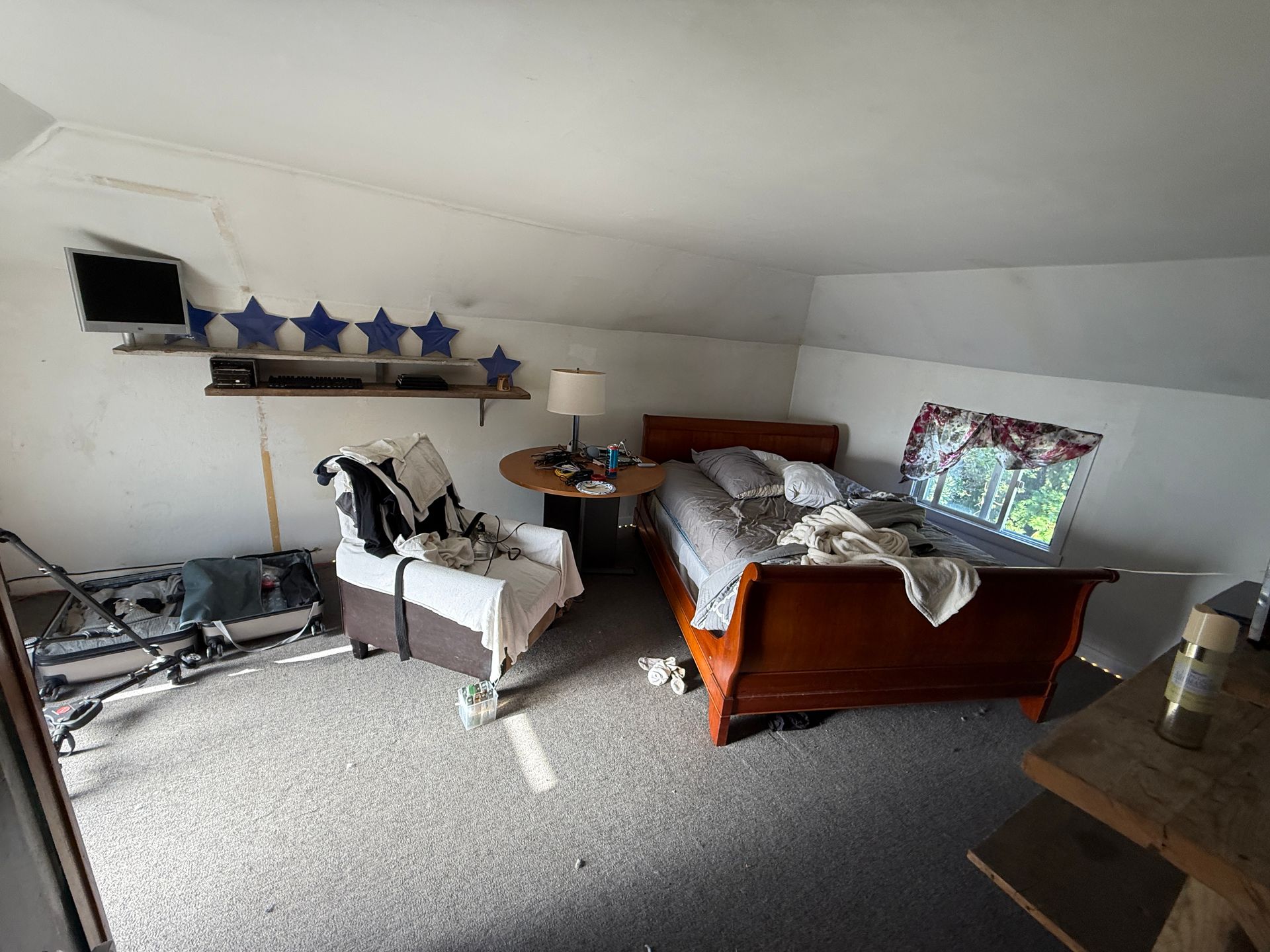 Bedroom with bed, chair, and TV; sloped ceiling.