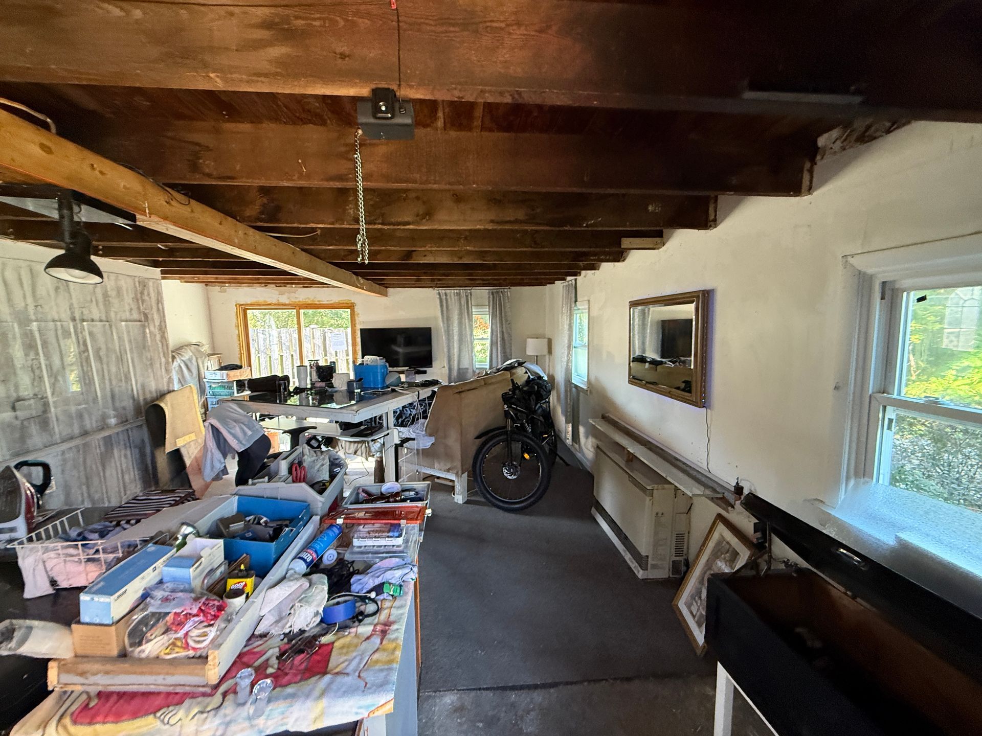 Workshop with exposed wooden beams. Tools, tables, bicycle, and windows.