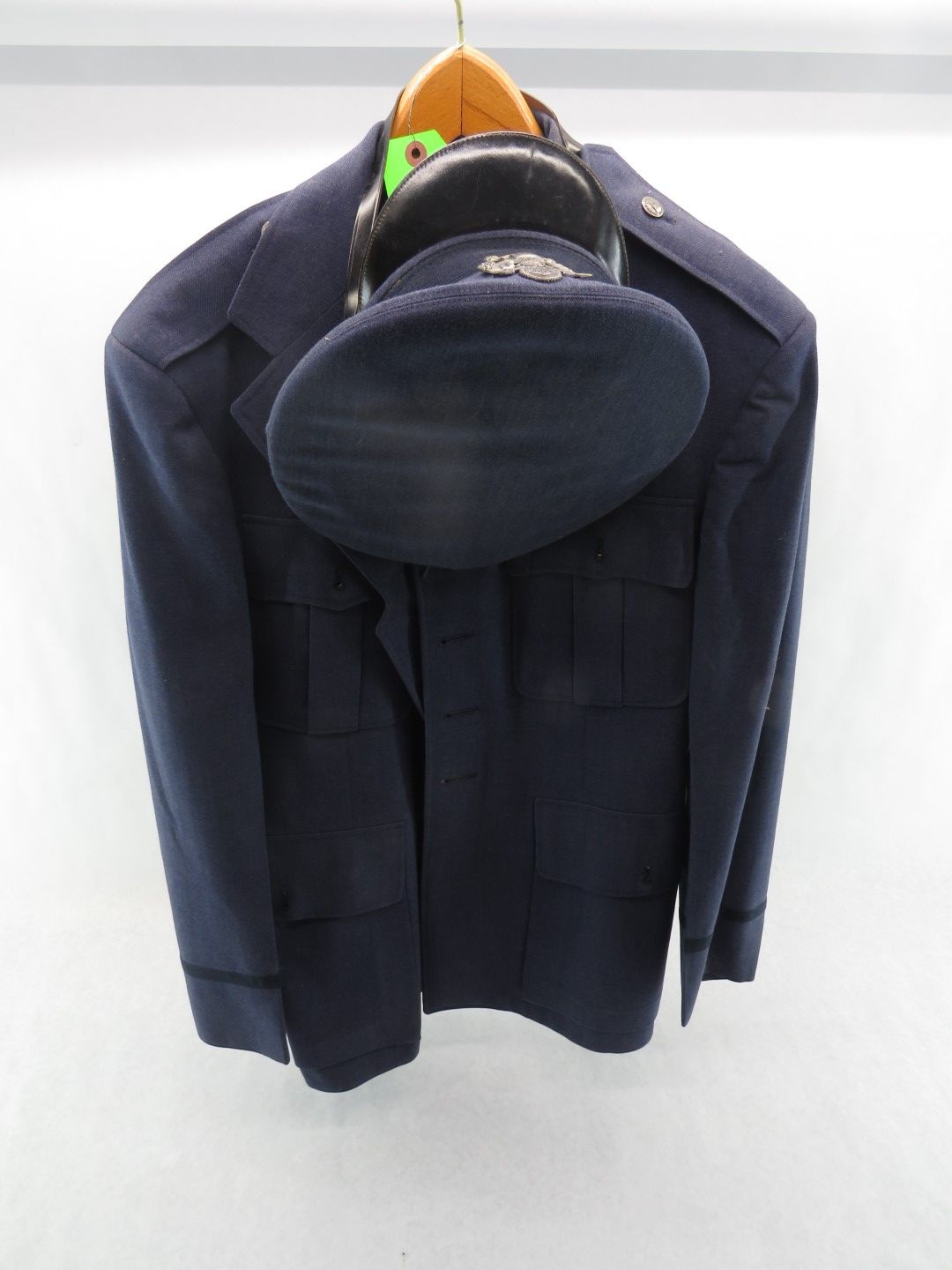 Blue Air Force uniform jacket and hat hanging on a wooden hanger against a white background.