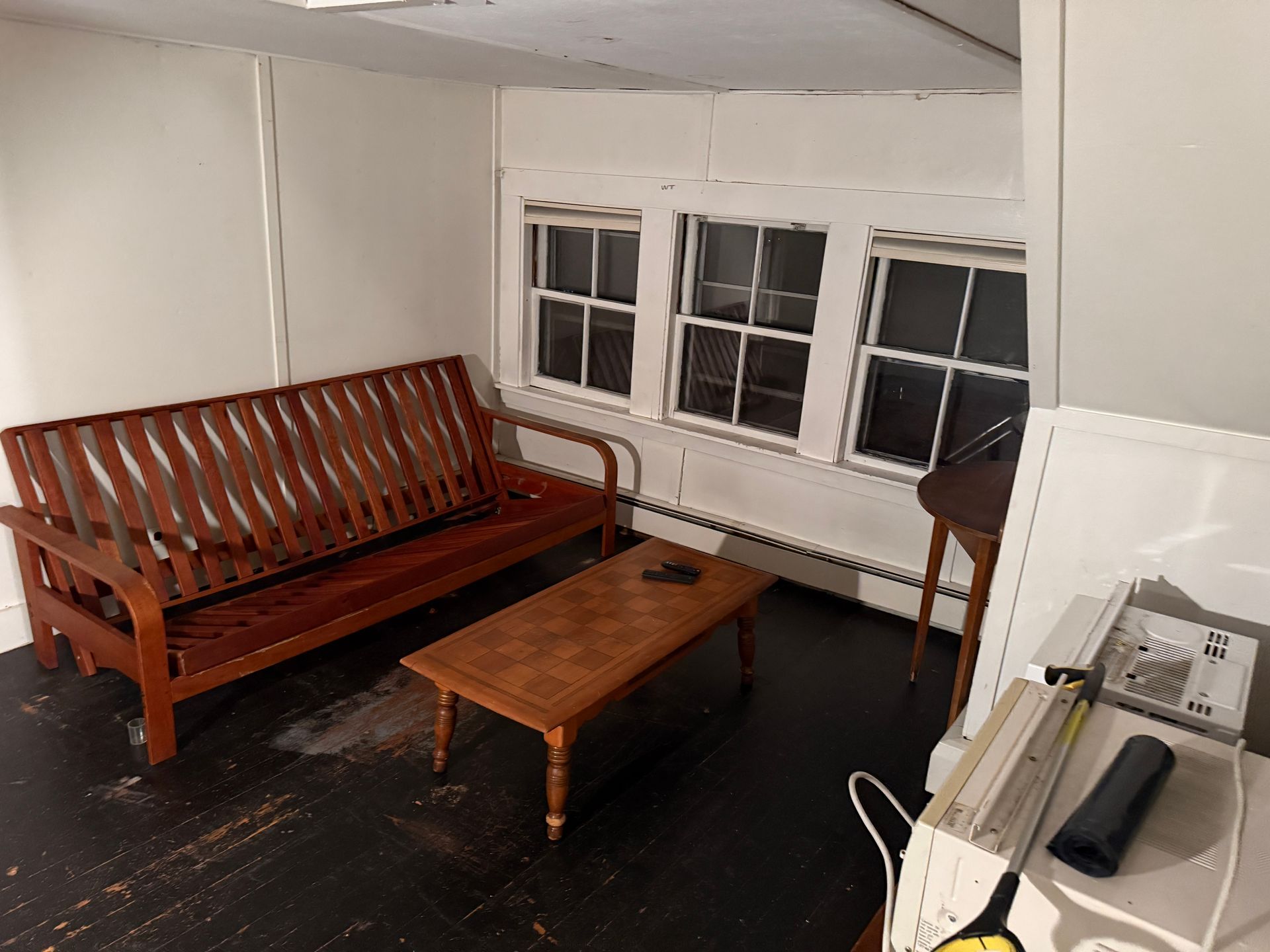 Living room with a futon, coffee table, and windows.
