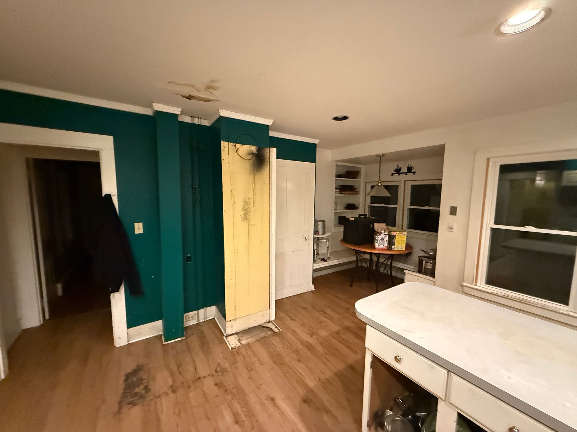 Interior kitchen with teal accents, white trim, and light wood floors. A cabinet and a door are visible.