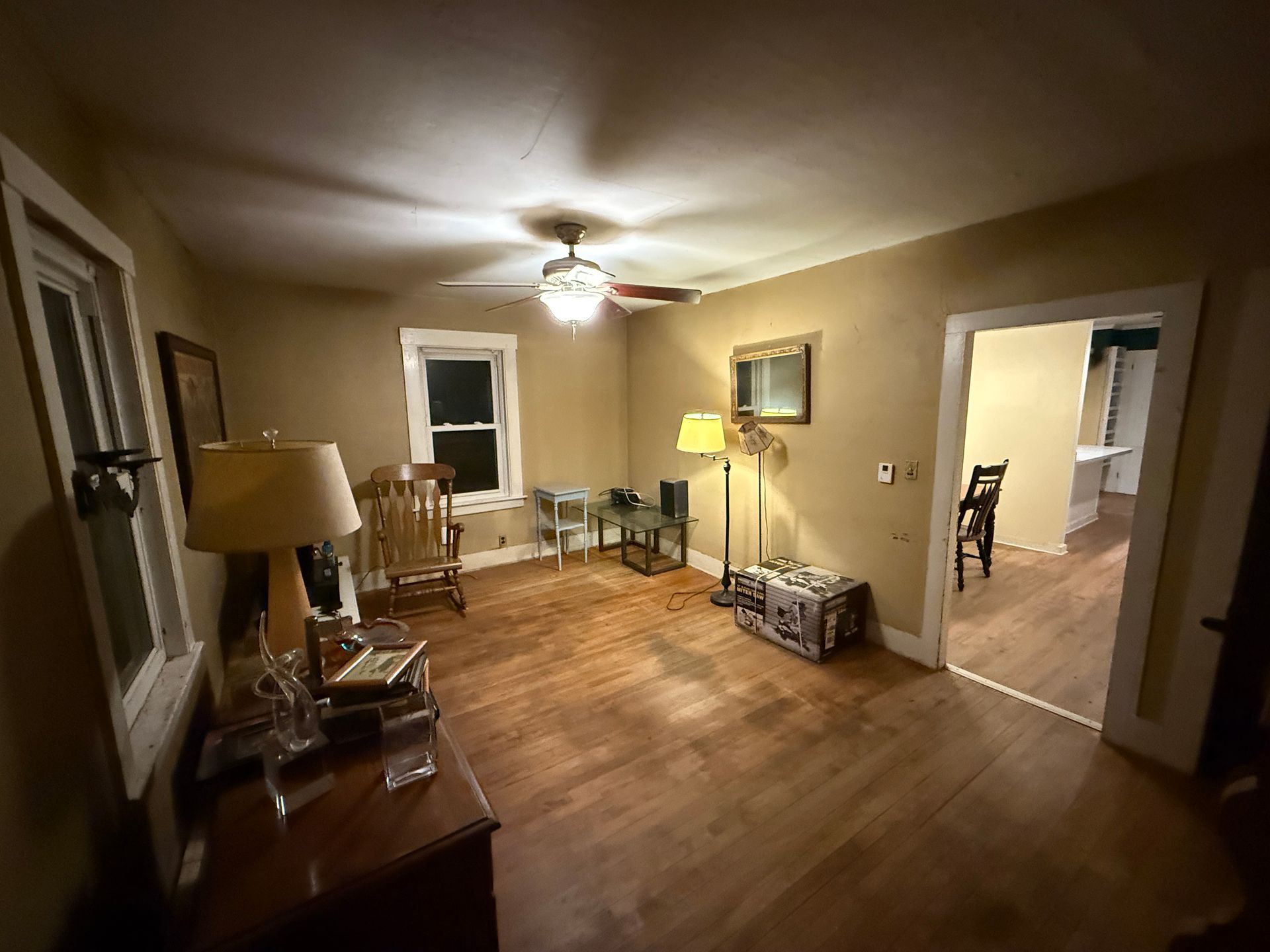 A  room with wood floors, furniture, and an open doorway to another room.