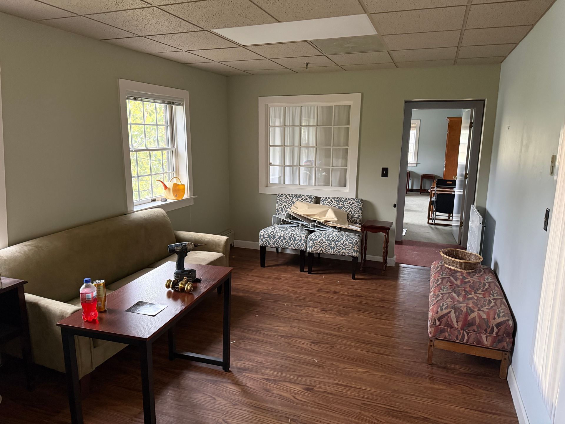 Living room with a green wall, windows, a couch, chairs, and a doorway.