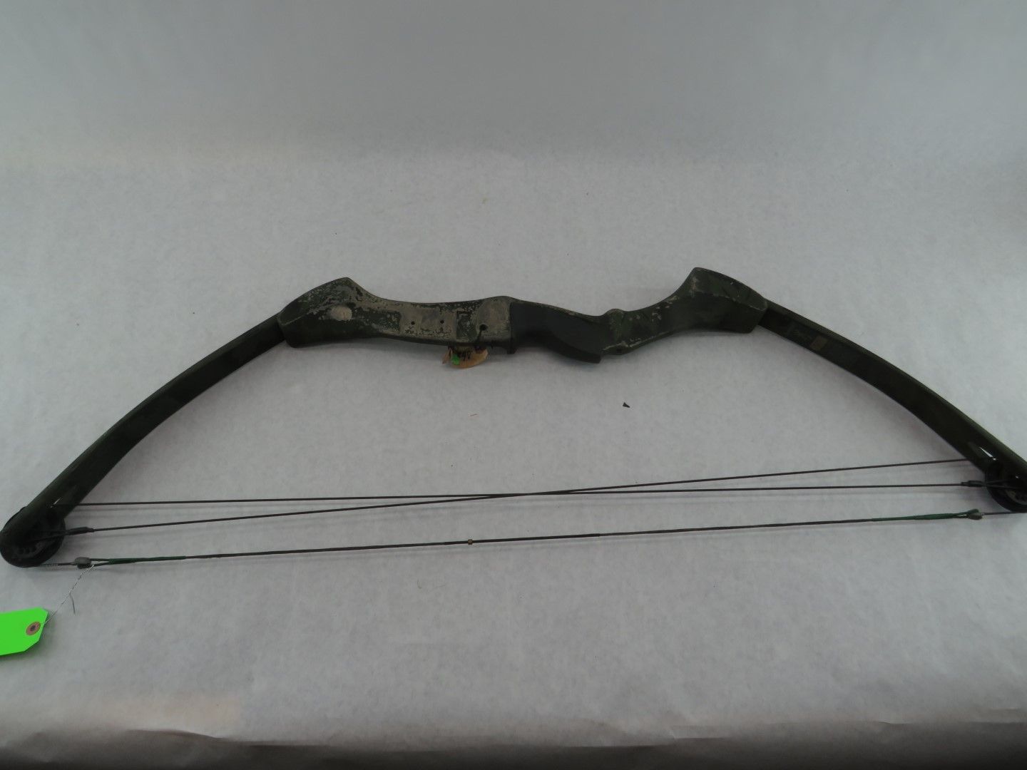 Compound bow with black limbs and string, lying on a white surface.
