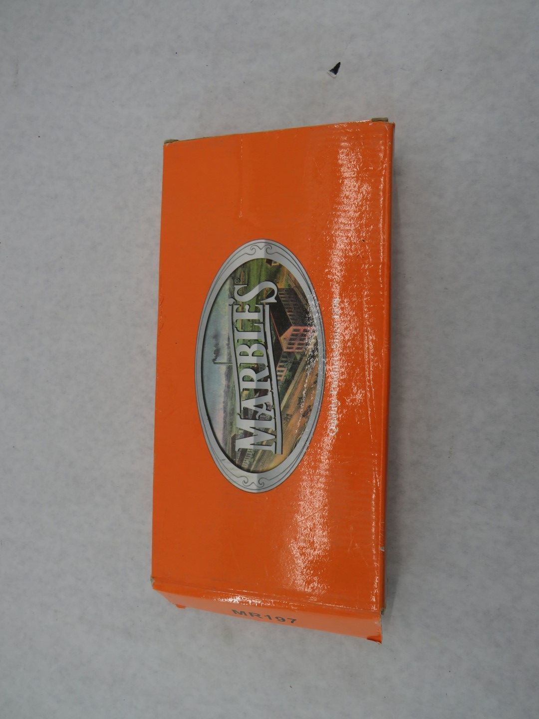 Orange book with an oval-shaped image on the front, of a building, ladder, and trees.