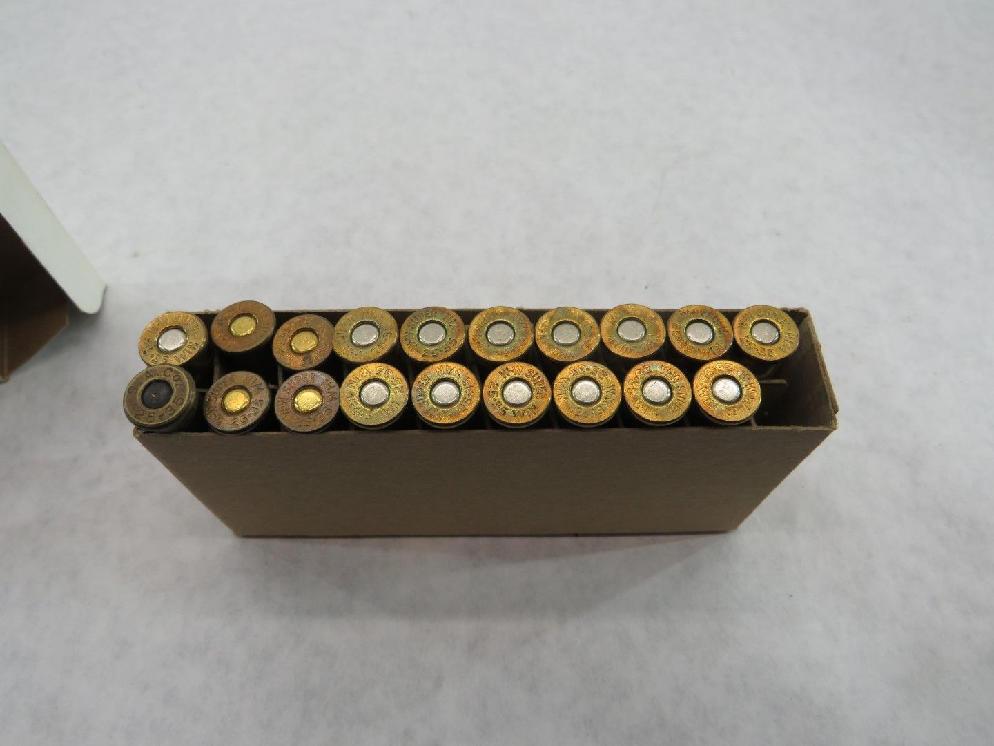 Box of ammunition with brass casings and silver primers.