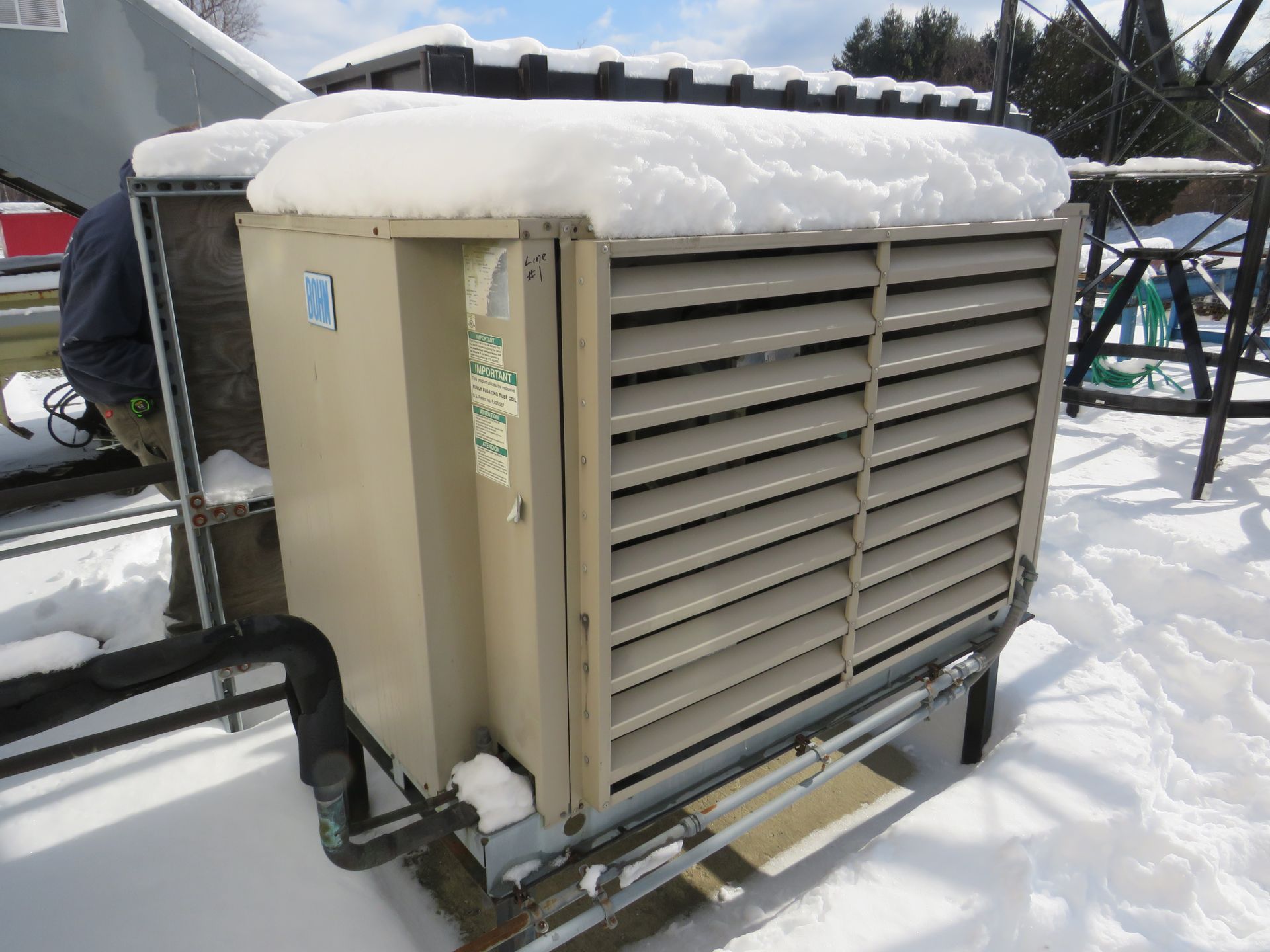 Air conditioning unit covered in snow on a snowy rooftop.