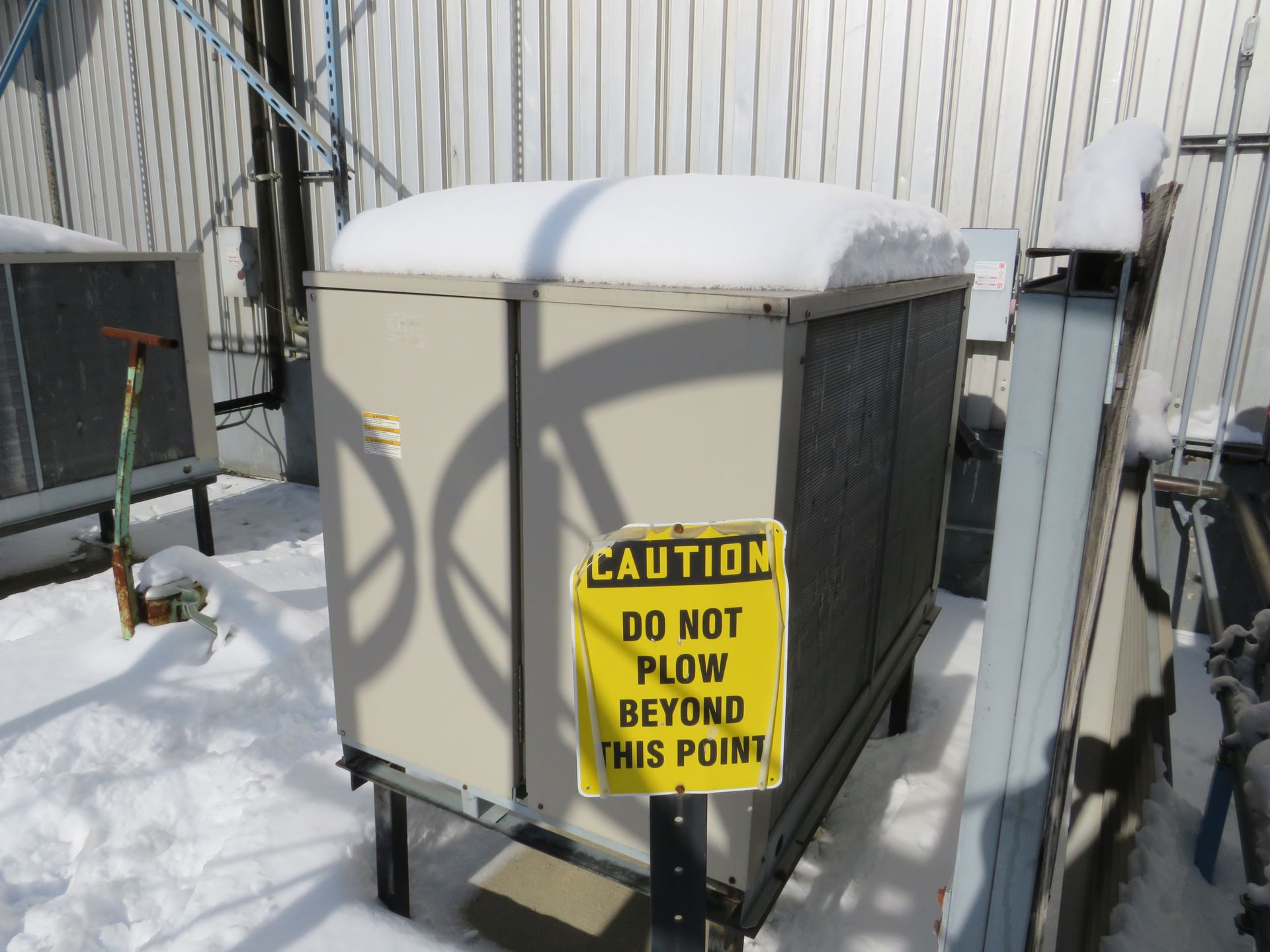 Snow-covered industrial equipment with a warning sign reading 