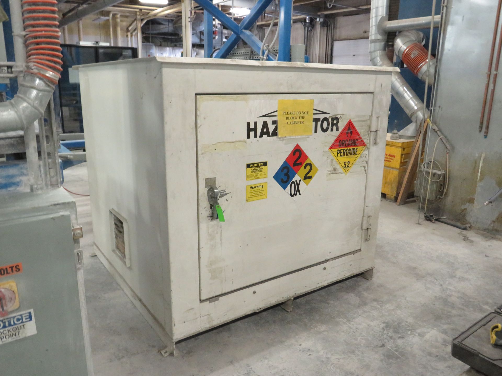 Hazardous materials storage cabinet with warning labels in an industrial setting.