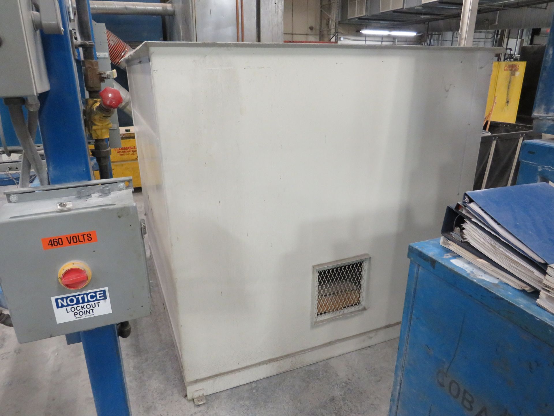 Large, off-white industrial metal box with a vent, in a factory setting.
