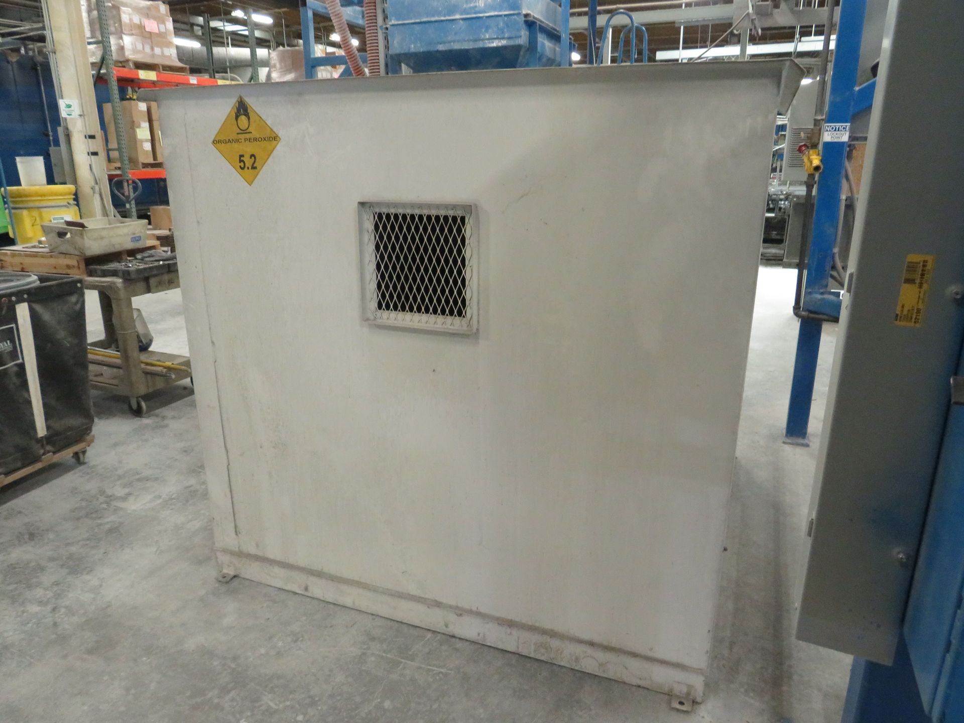 Large, white industrial container with a vent and hazard symbol in a warehouse setting.