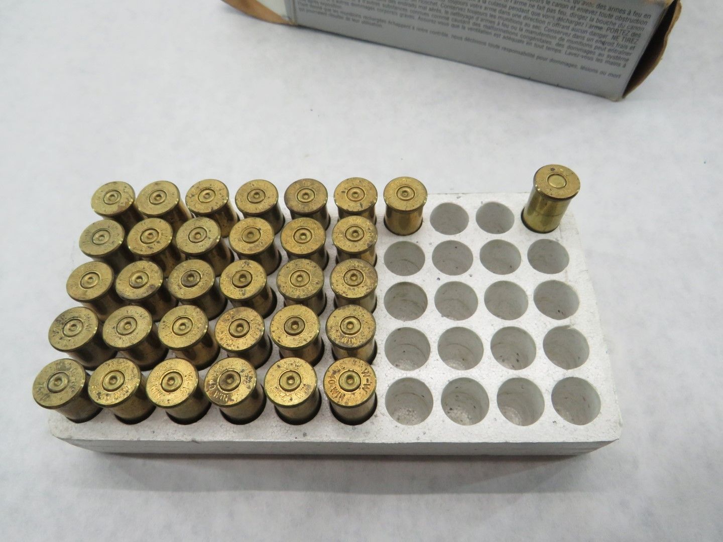 Cartridge ammunition in a cardboard tray. Brass casings with black primers.