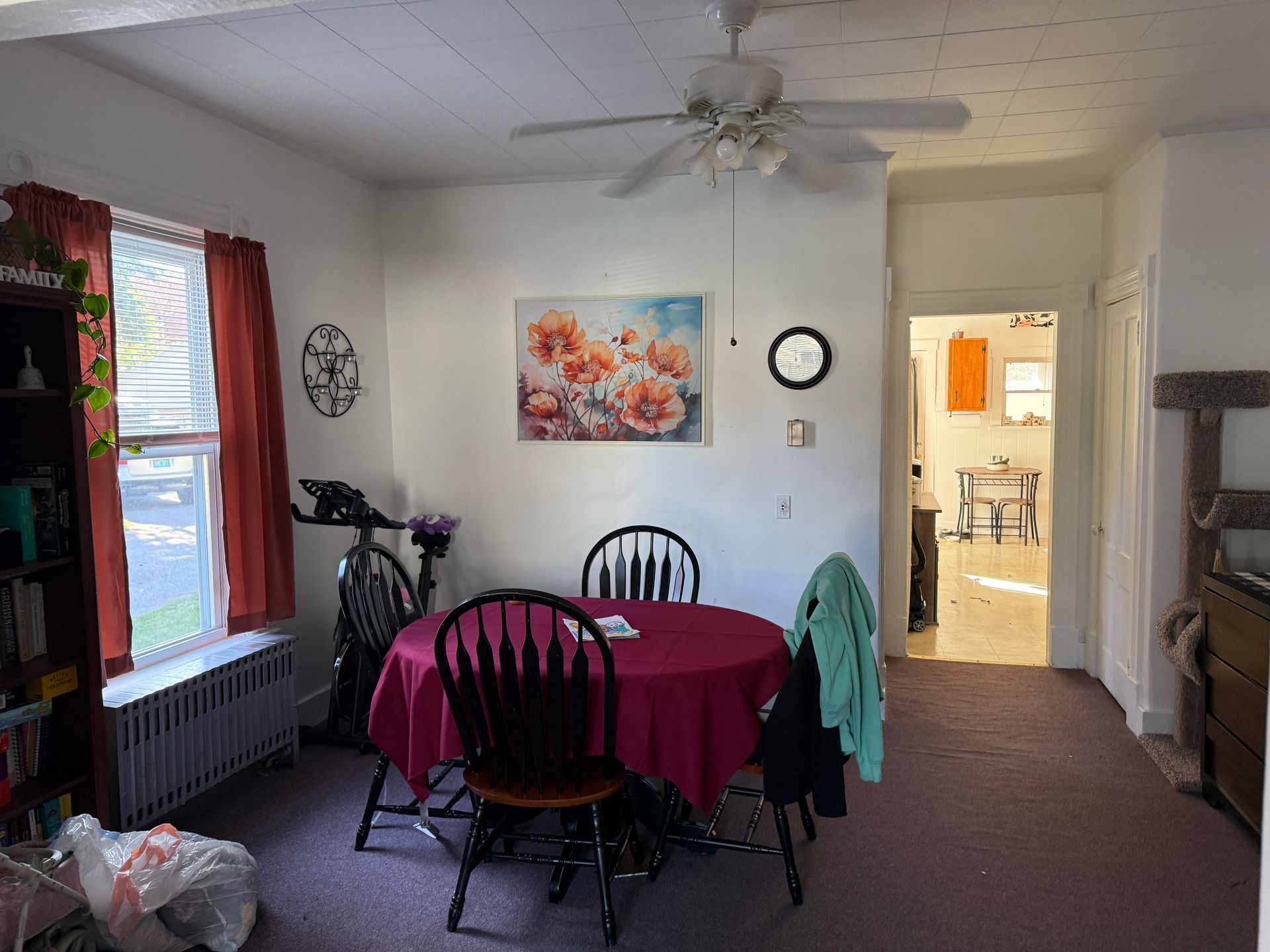 Dining room with table, chairs, art, and doorway to another room.