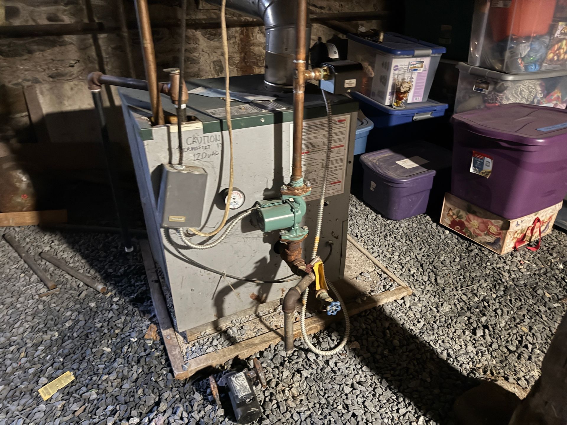 A heating boiler in a basement setting with copper pipes and various attachments.