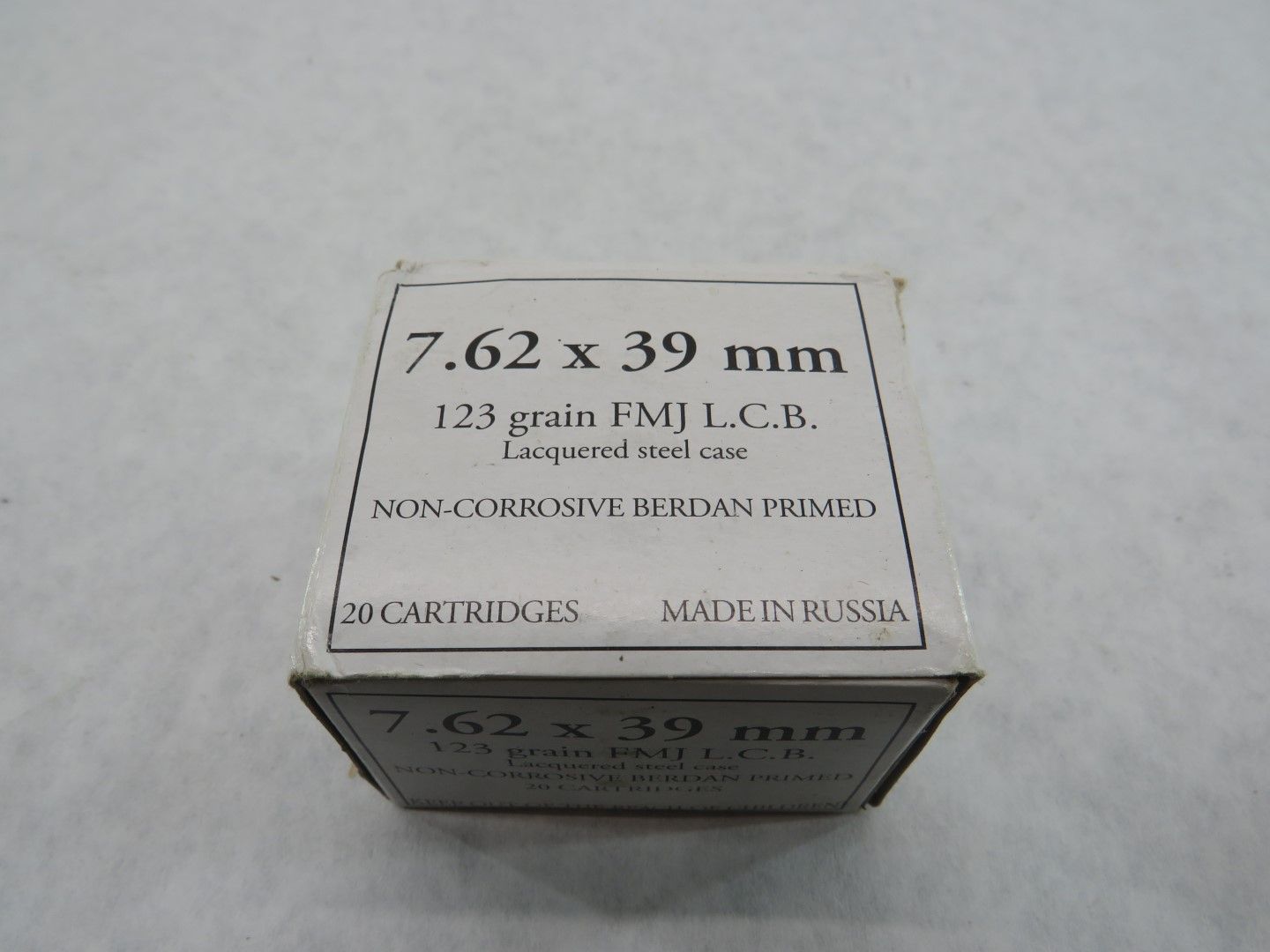 Box of 7.62 x 39 mm ammunition cartridges. White box with black text indicating bullet type and manufacturer (Russia).