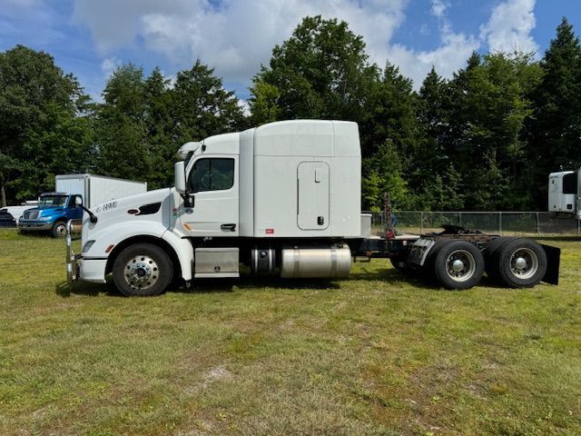 White semi-truck parked on grass. Trees in background.