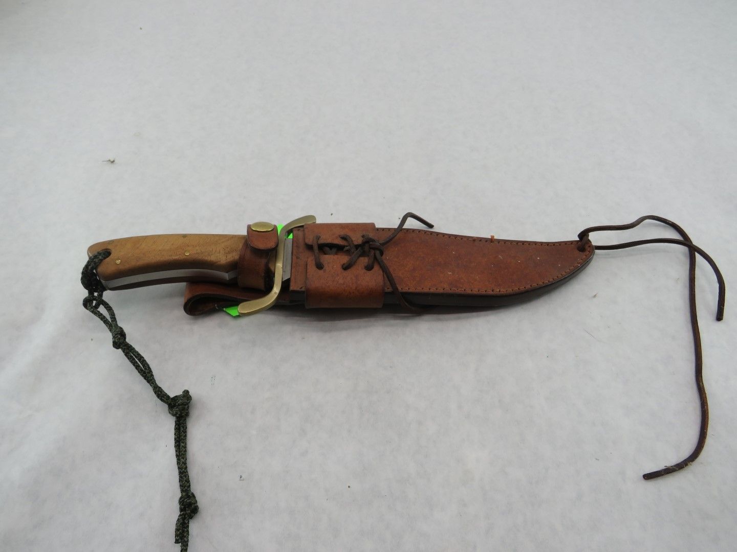 Knife in a brown leather sheath with a wooden handle.