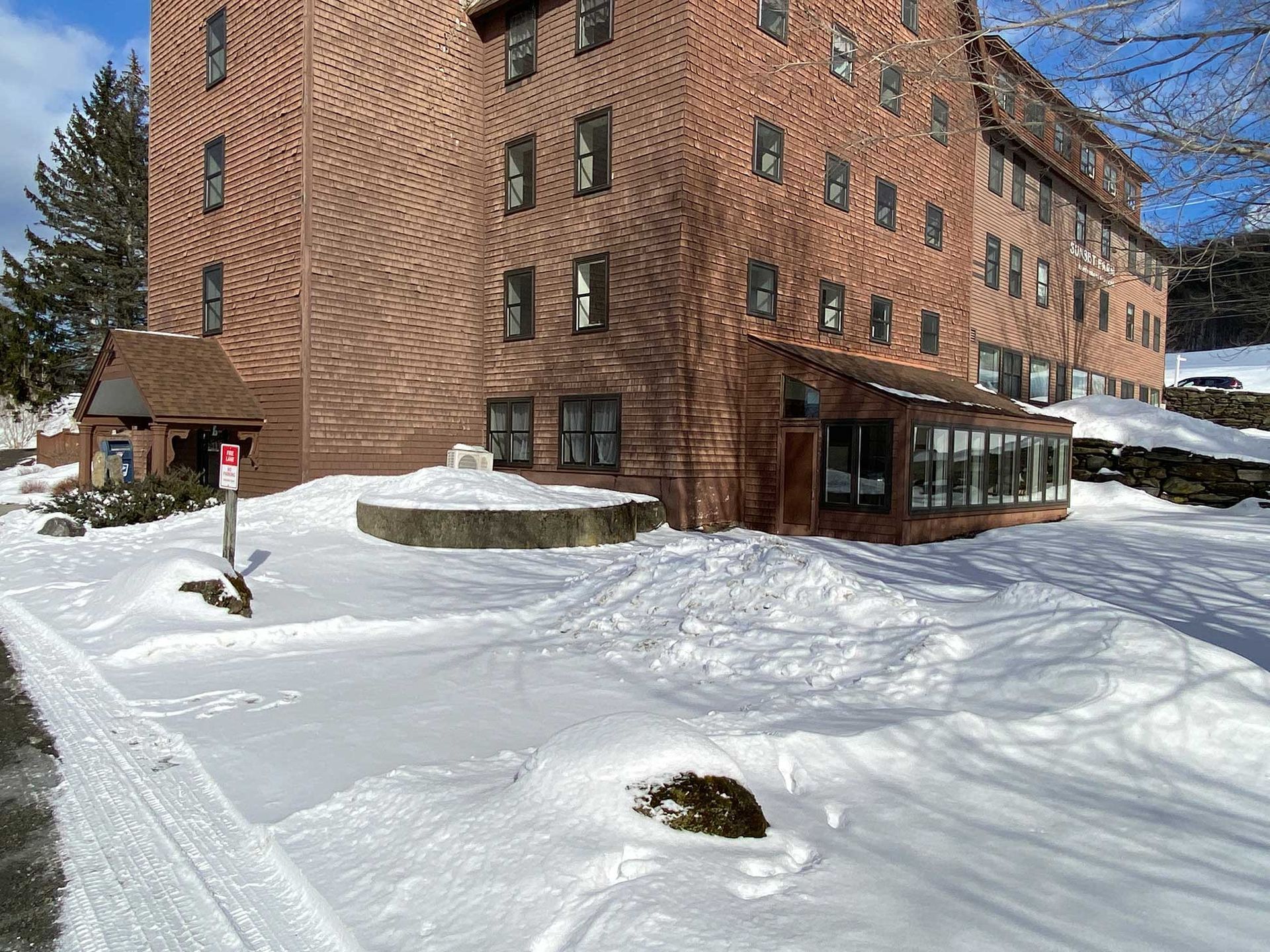 Brick building with snow-covered ground, a round structure, and a small wooden structure with a porch.