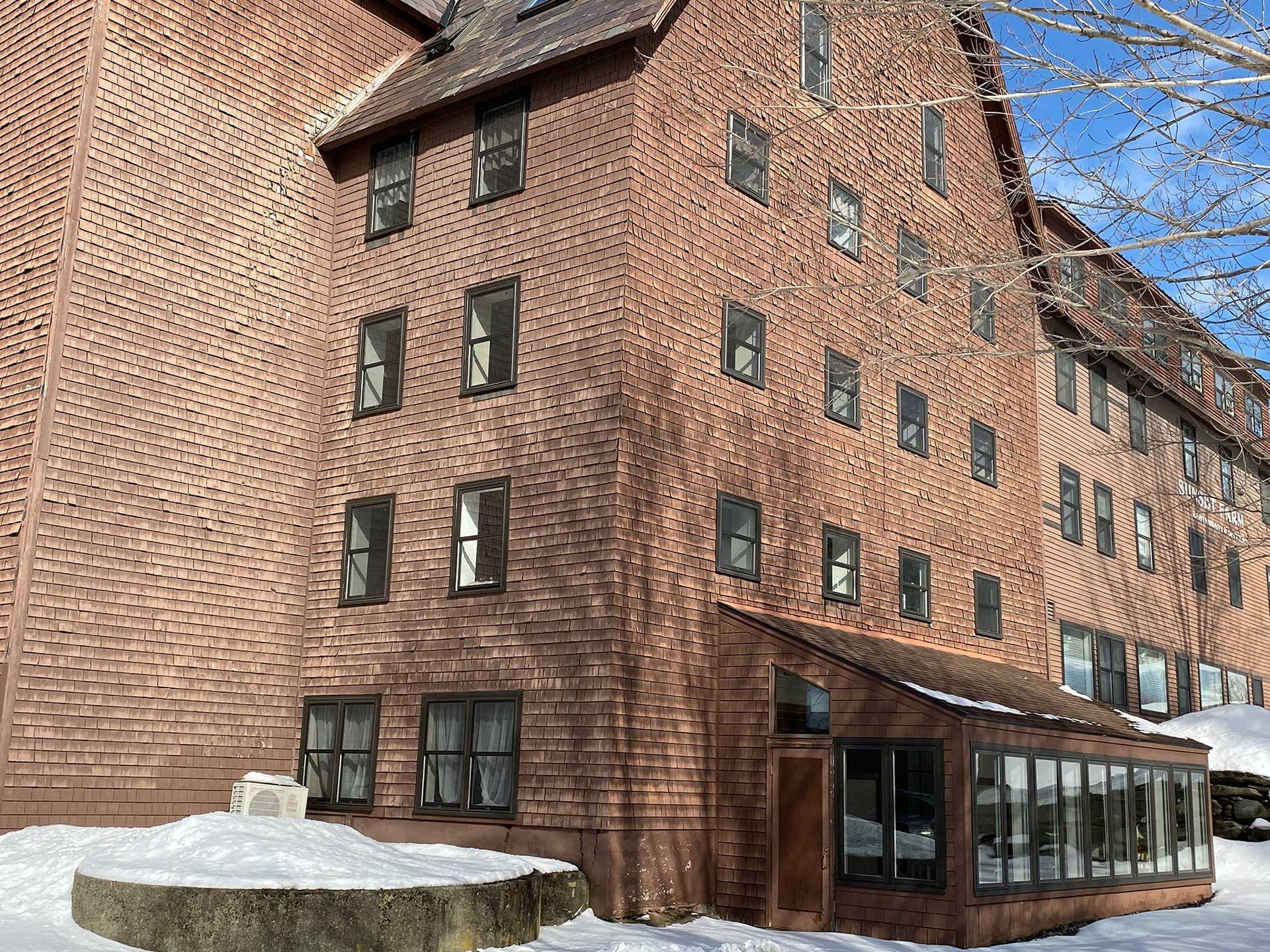 Brick building with many windows and snow on the ground.