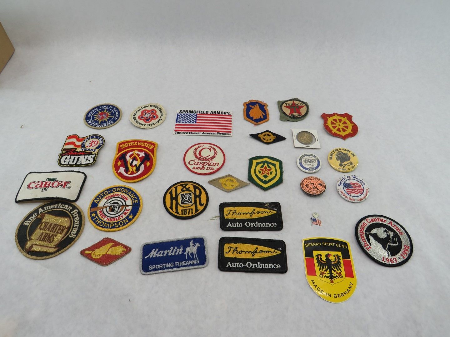 Collection of vintage patches and pins with various logos and designs on a white surface.