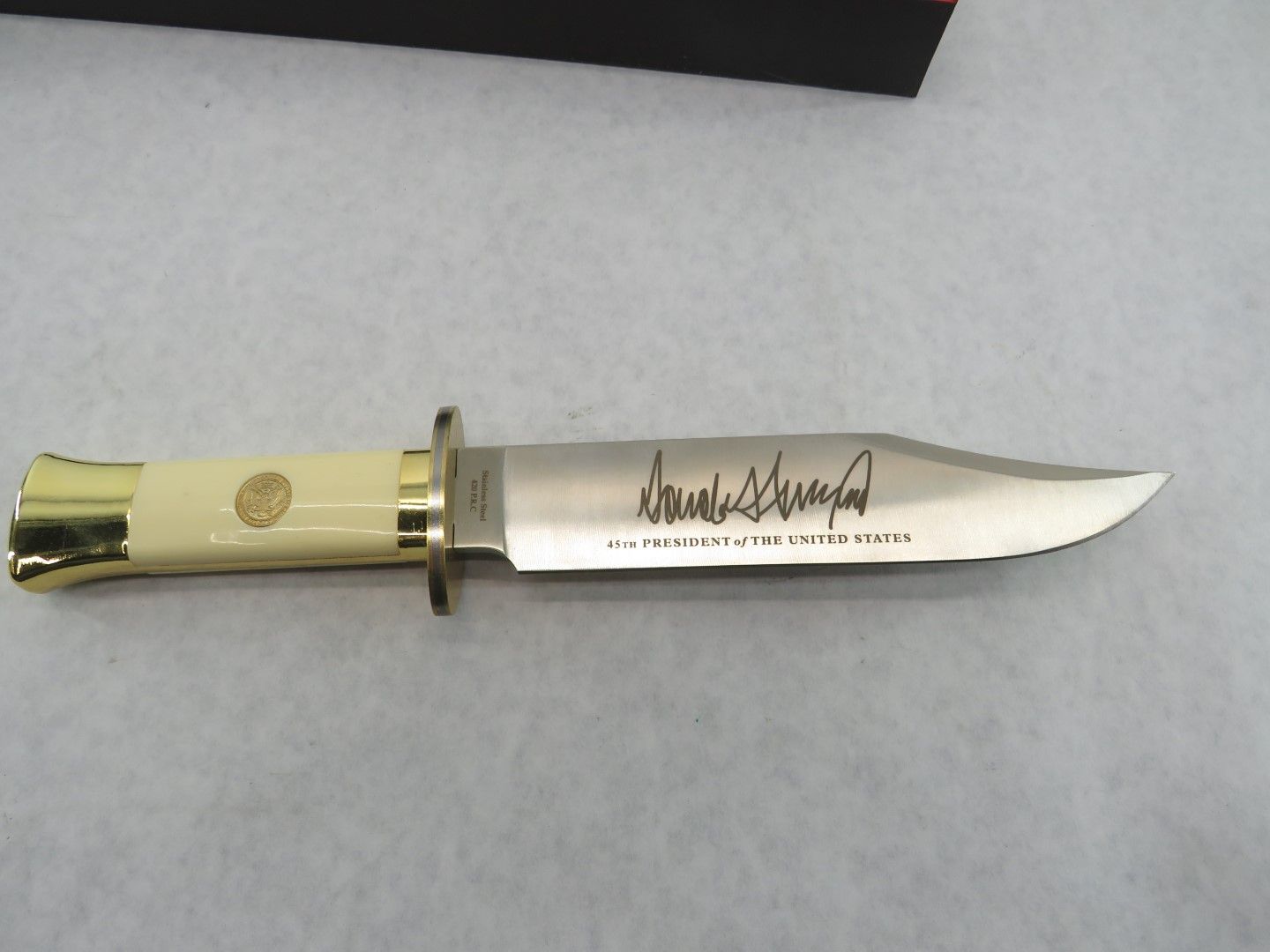 Cream-handled knife with a silver blade. It has gold accents, and an engraved signature on the blade.
