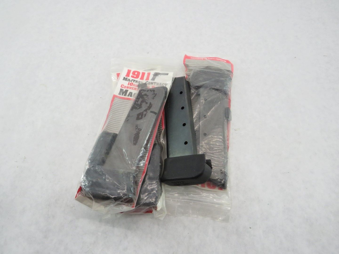 Three black gun magazines in plastic packaging.