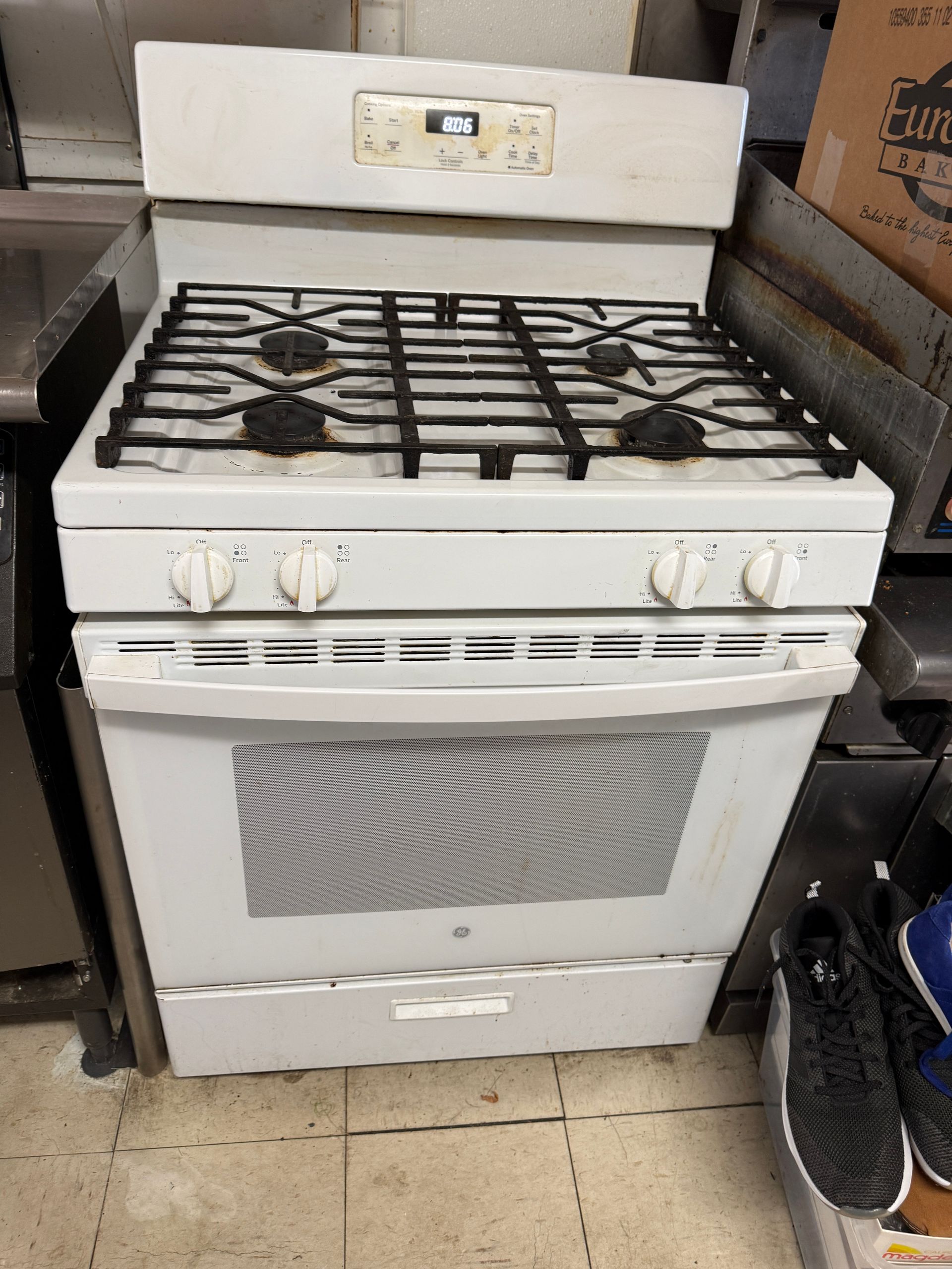 White gas range with black grates, oven, and control panel.