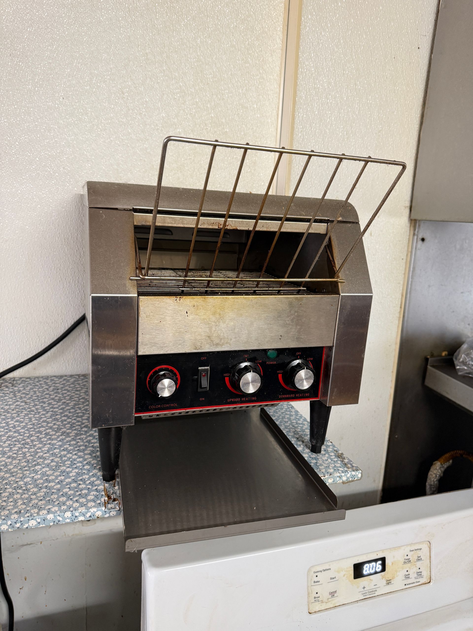 Stainless steel commercial toaster with three dials and a wire rack on a countertop.