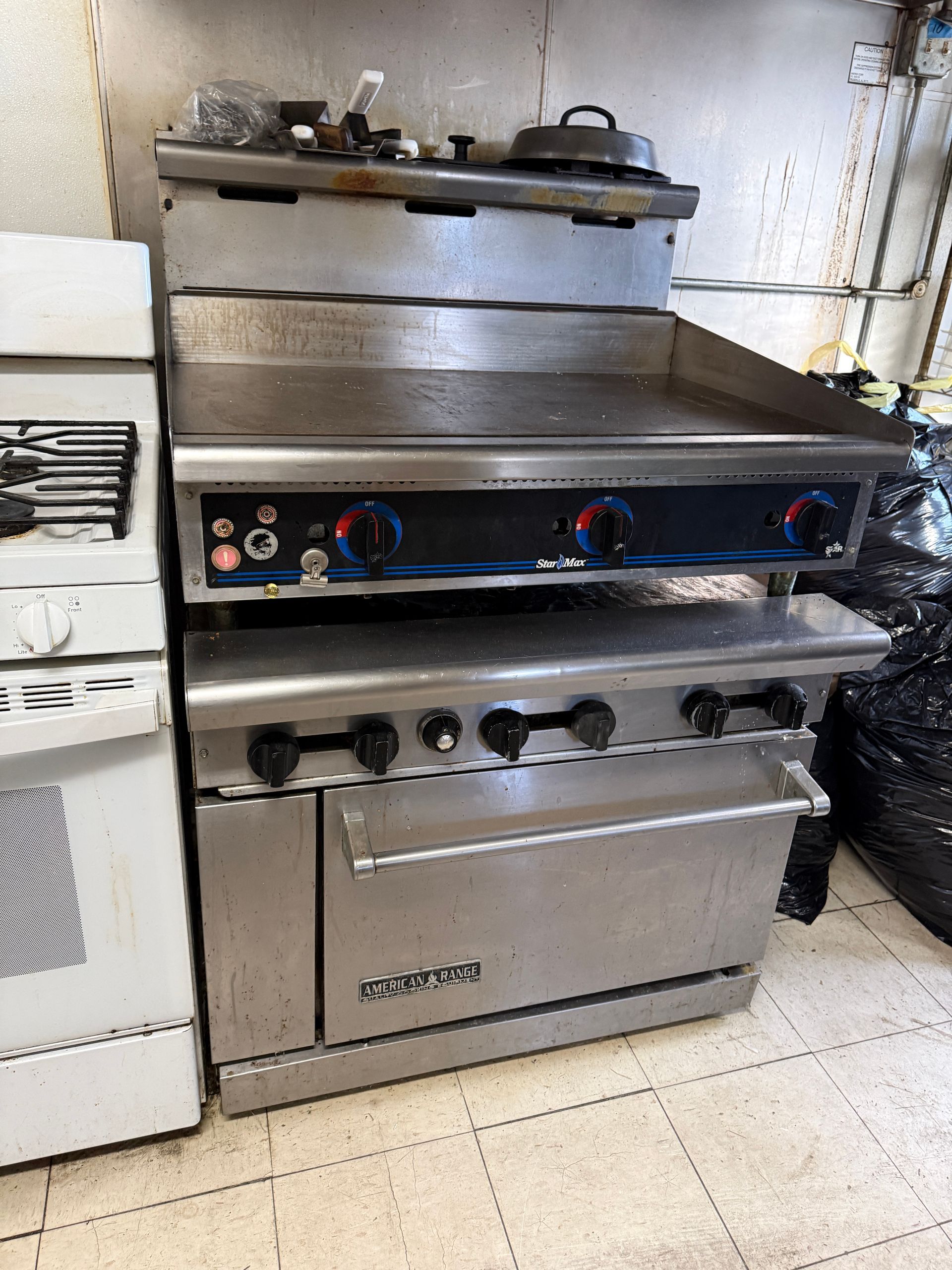 Commercial kitchen range with griddle, oven, and burners, stainless steel.