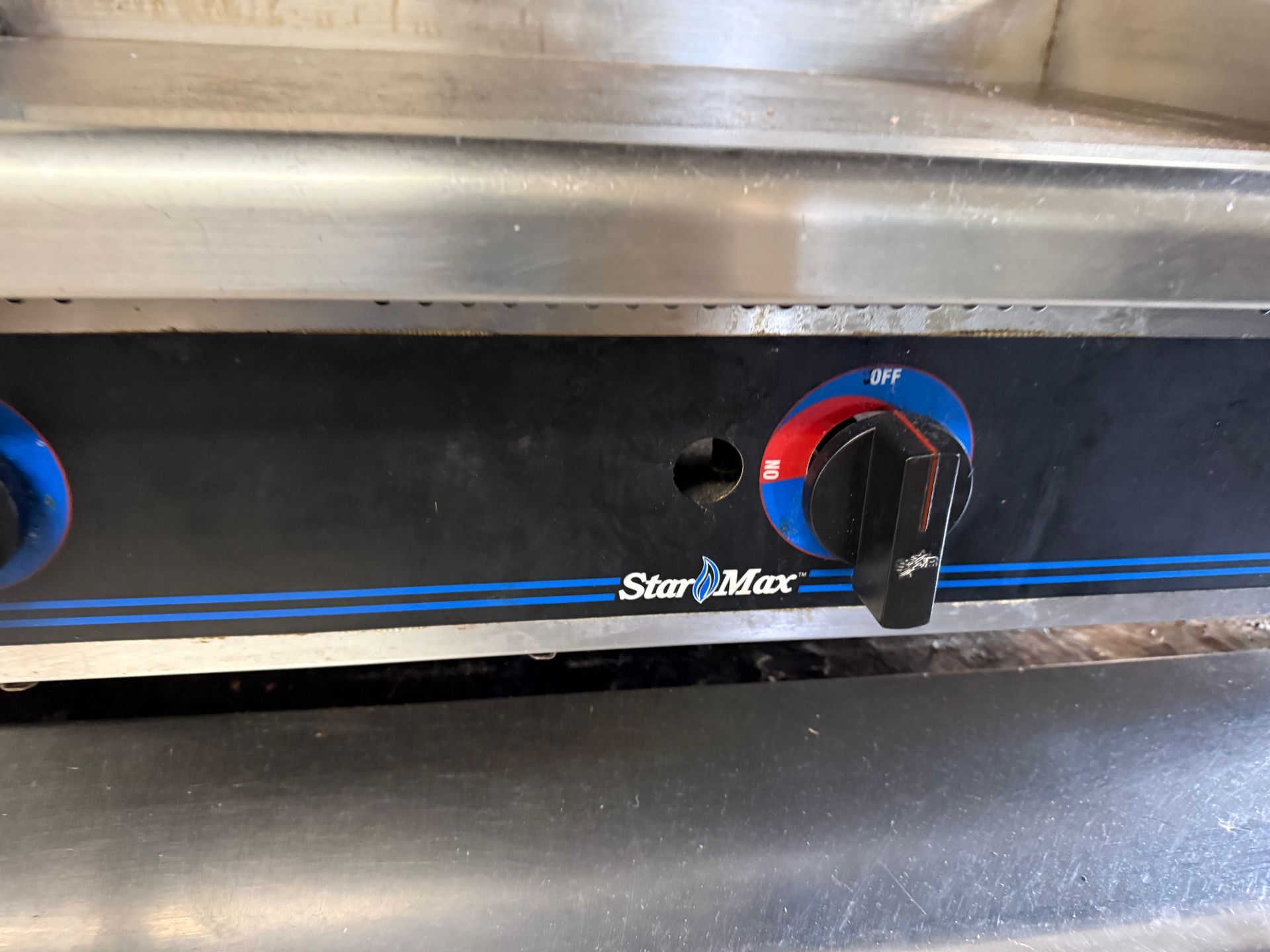 Close-up of a Star Max griddle control panel. Black with a blue stripe, dials in red and black, stainless steel.