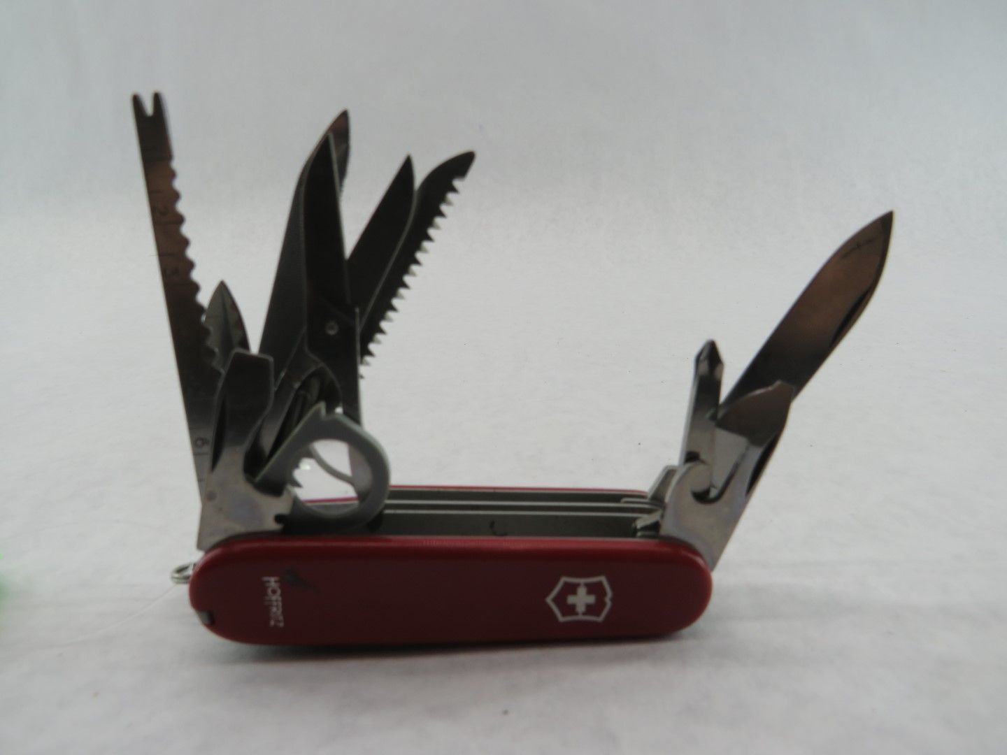 Red Swiss Army knife with various tools extended.