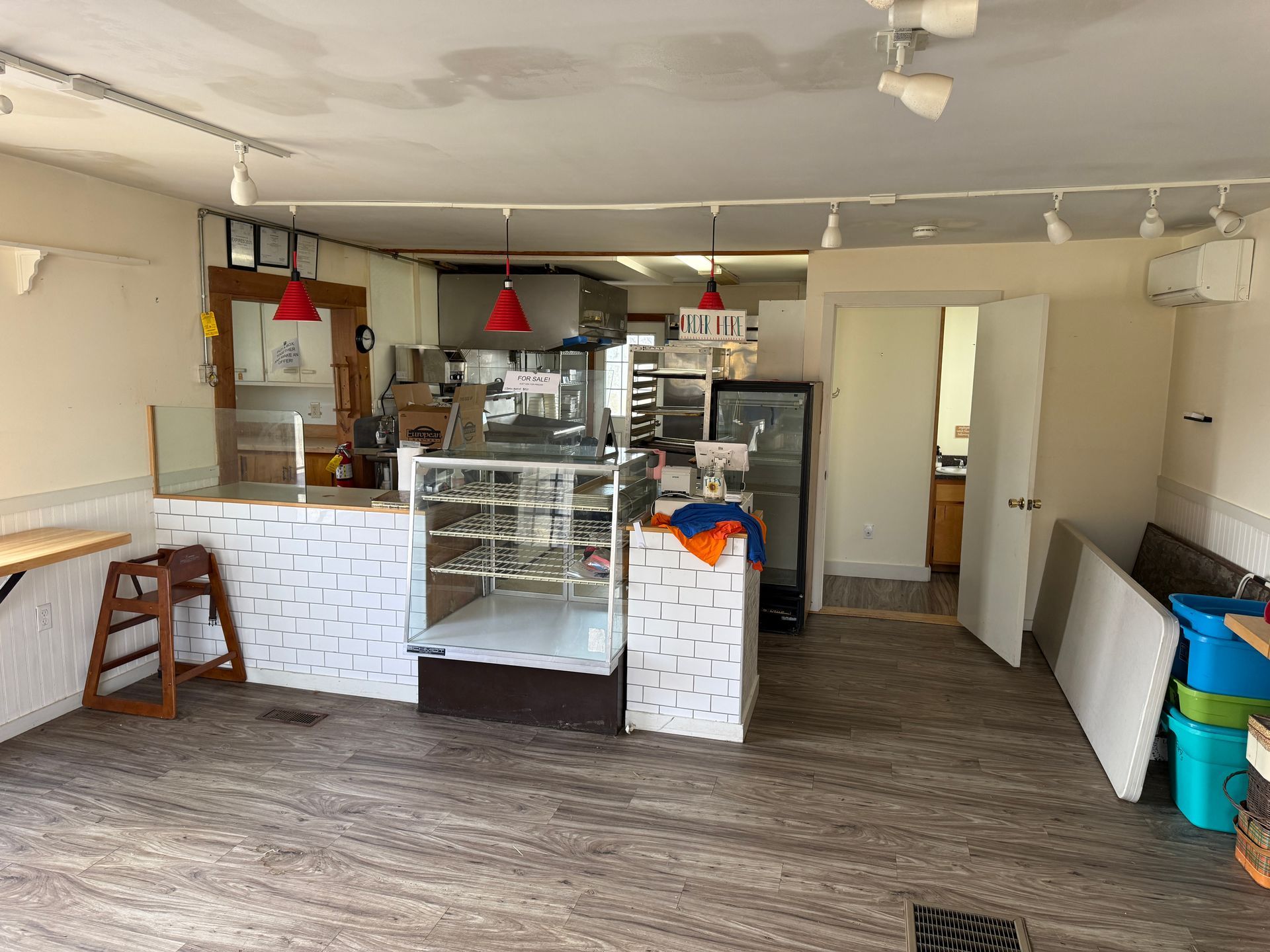 Interior of a bakery with display cases, kitchen visible in the back, and equipment.