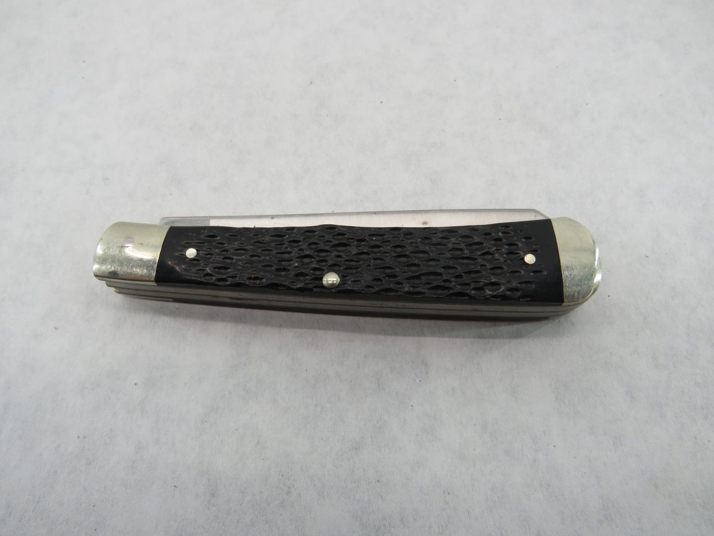 Closed pocketknife with black textured handle and silver bolster.