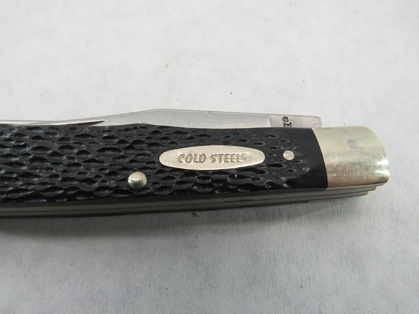 Close-up of a Cold Steel pocket knife with a black textured handle and a silver blade.