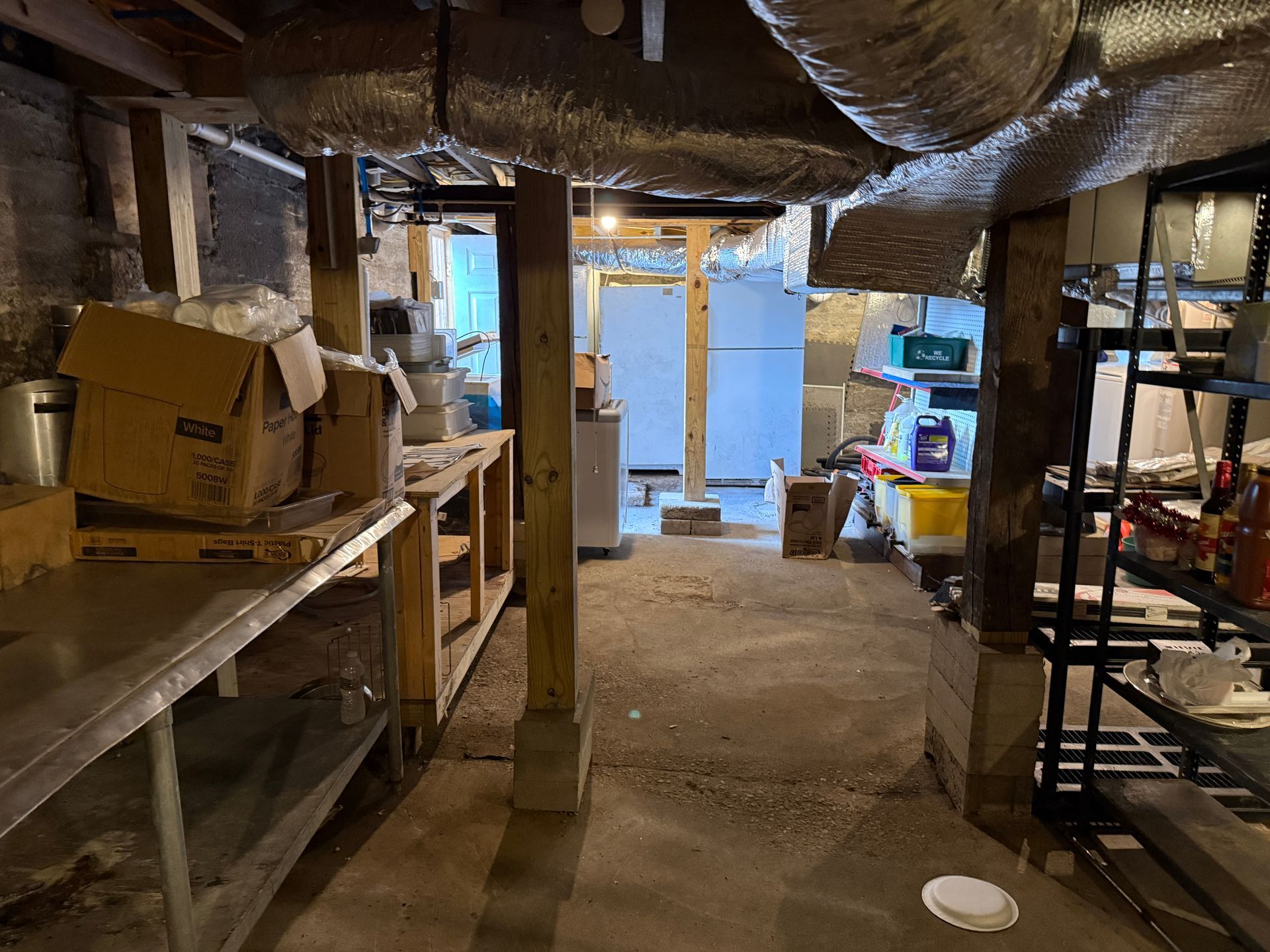 Basement storage area with metal shelving, boxes, and a stainless steel work surface.