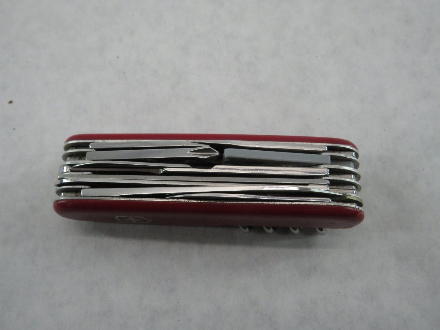 Red multi-tool with several metal implements, set against a white background.
