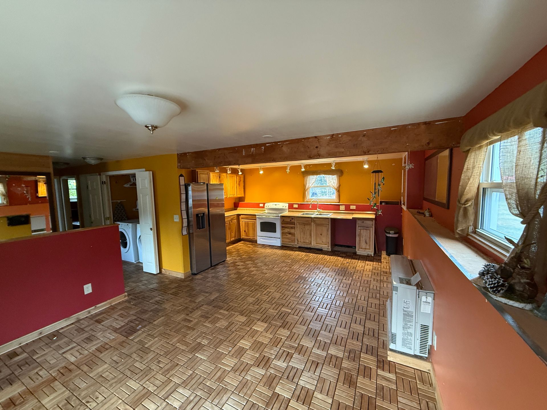 Open kitchen with wood floor, orange walls, and wood cabinets.