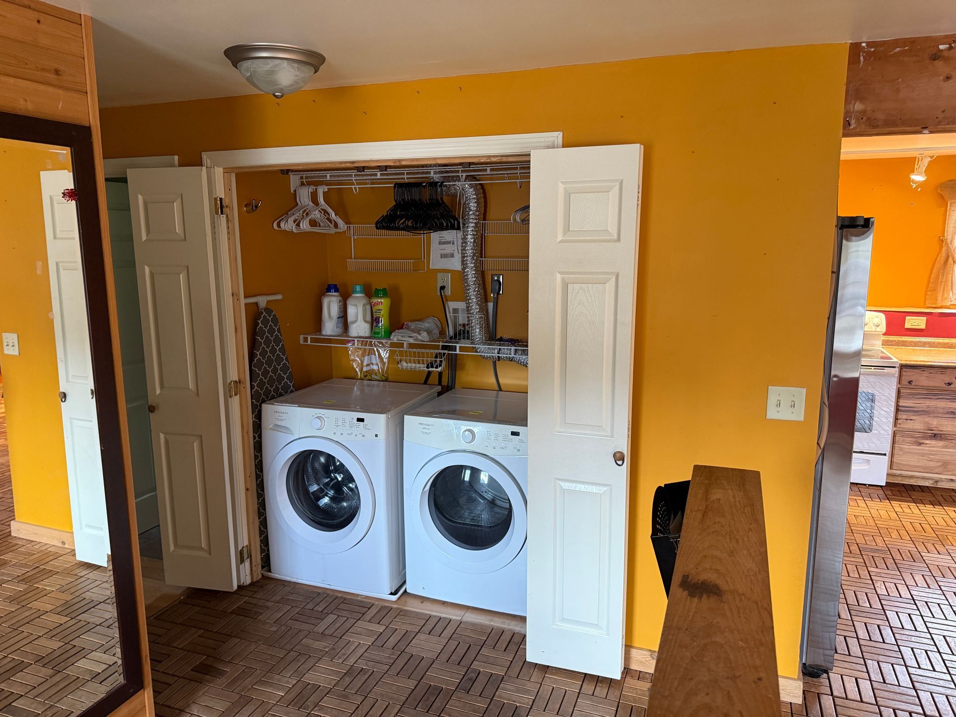 Laundry room with white washer/dryer, yellow walls, and bi-fold doors.