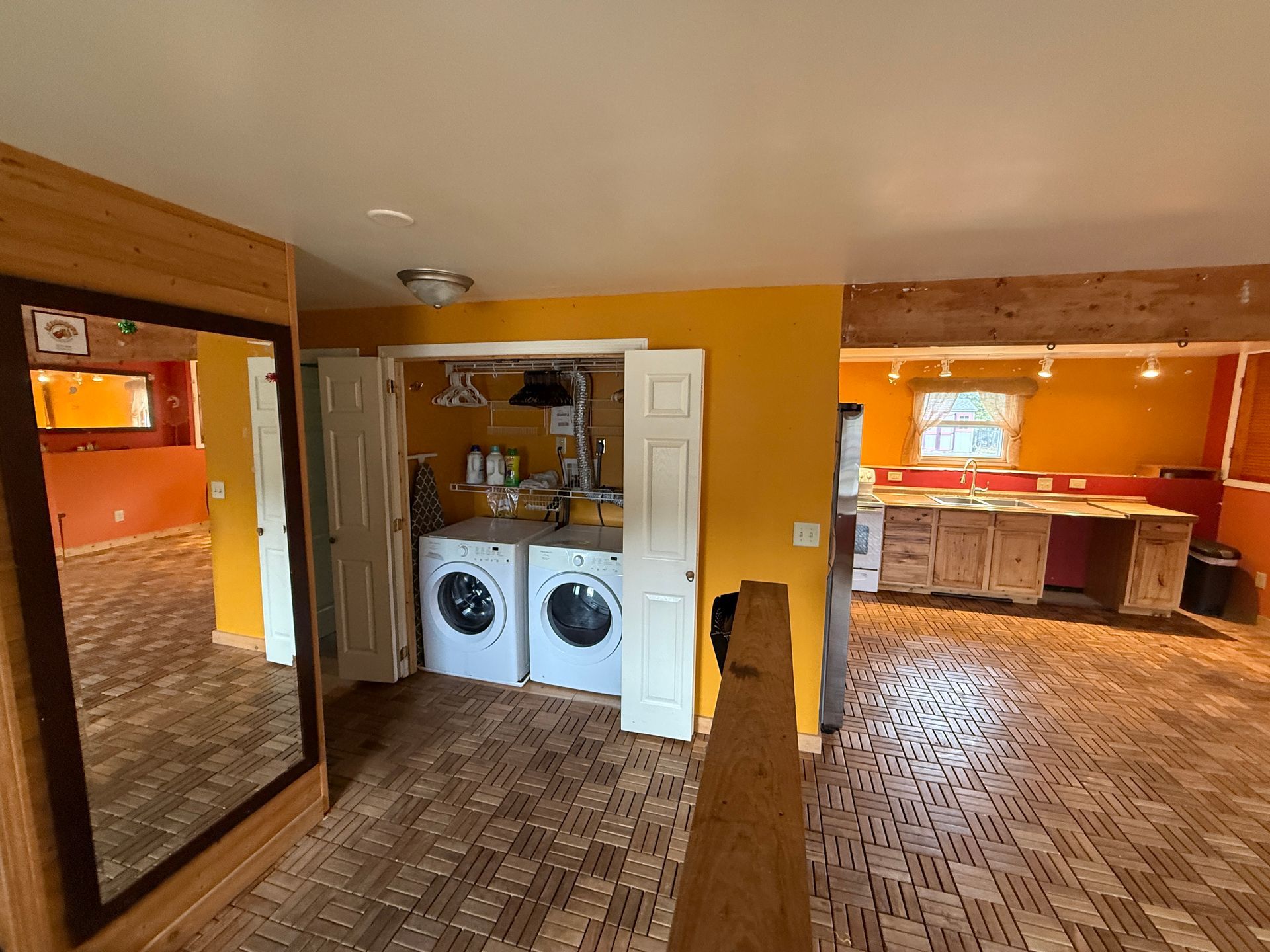 Laundry area with washer and dryer, adjacent to a kitchen with rustic cabinets.