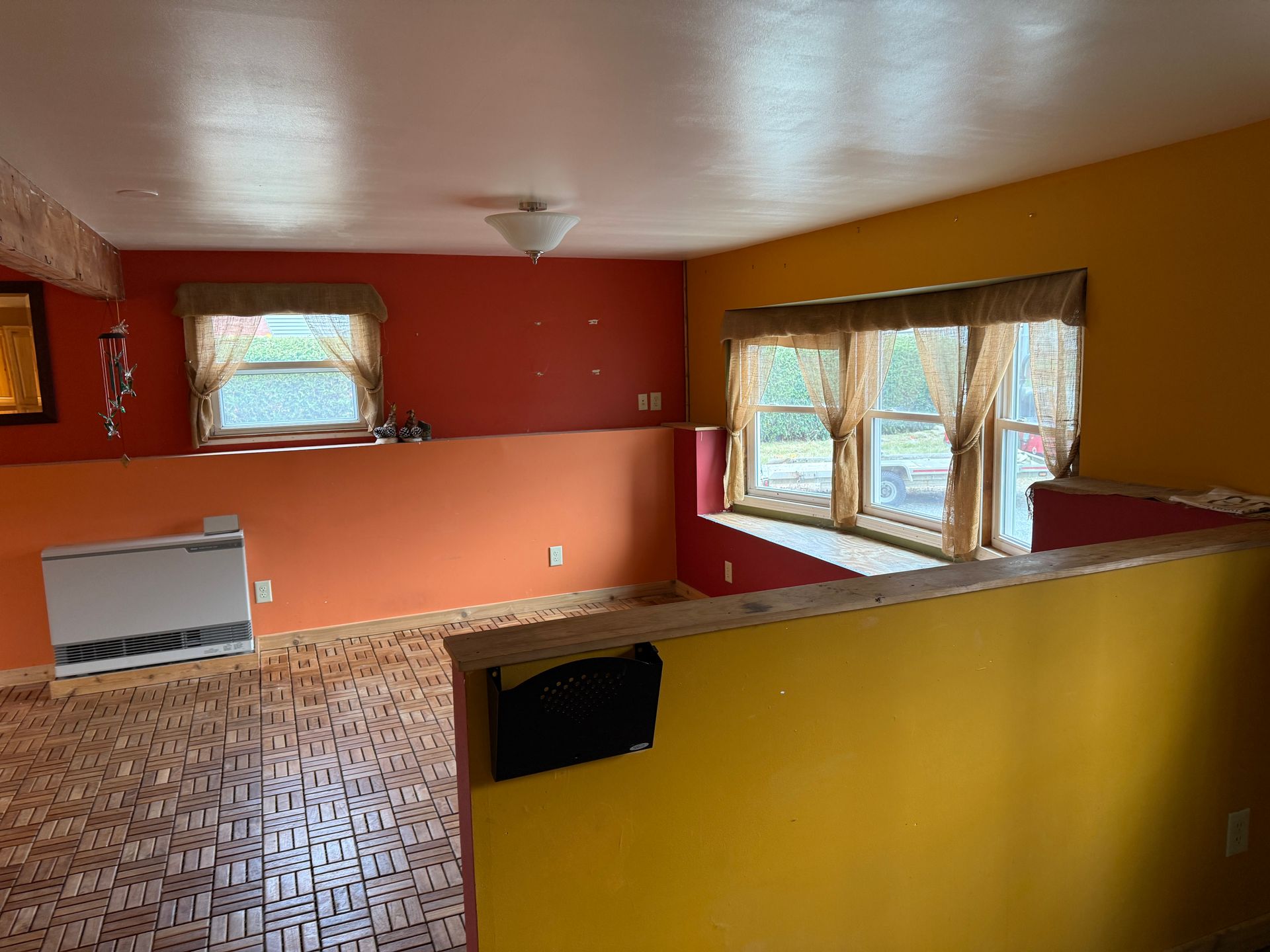 Interior view of a room with orange, red and yellow walls, a window seat, and wood-like flooring.