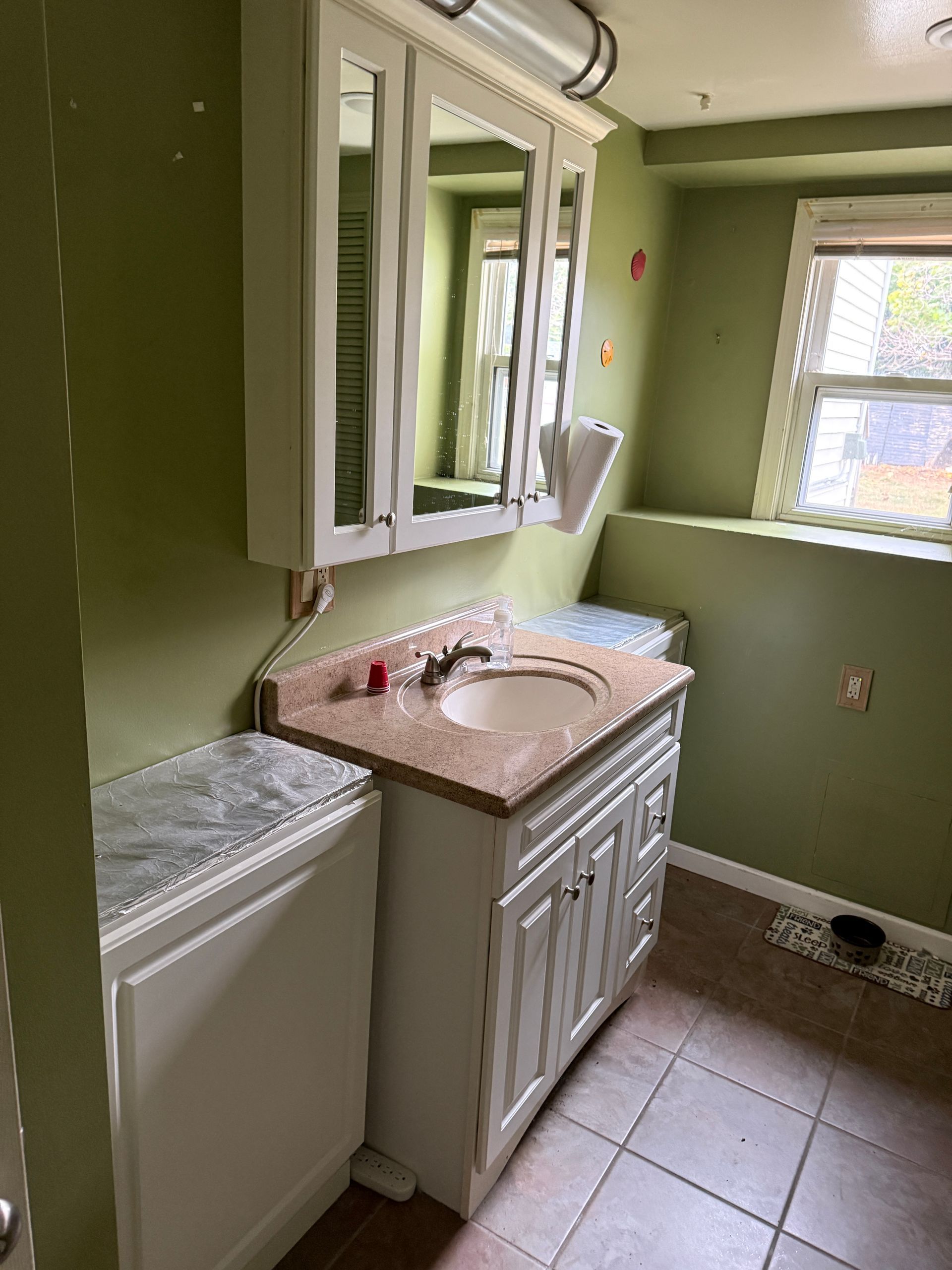 Bathroom with green walls, white vanity, and a window.